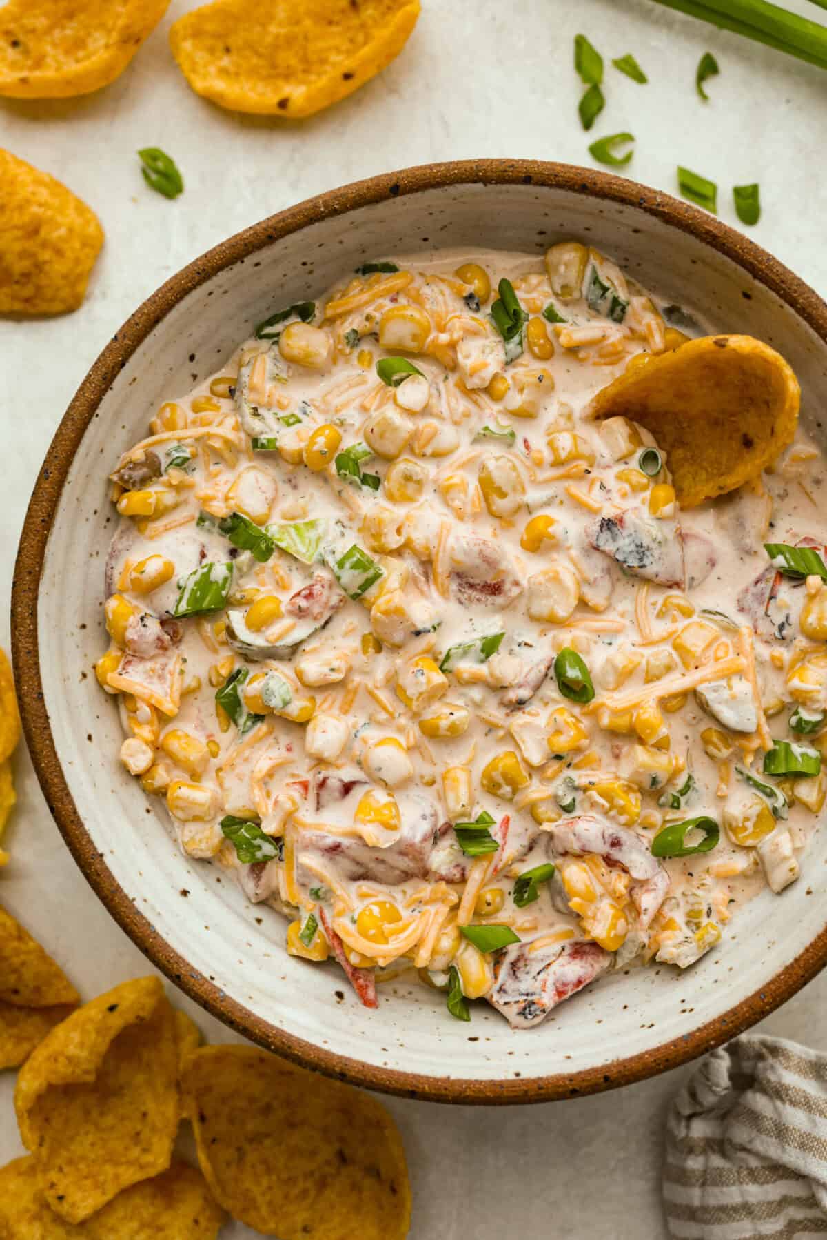 Crack Corn Dip is creamy, cheesy, and loaded with bold flavor! Sweet corn and a custom spice blend give it a fun twist, making it the ultimate scoopable snack for summer hangouts. Overhead shot of crack corn dip in a serving bowl with corn chips.