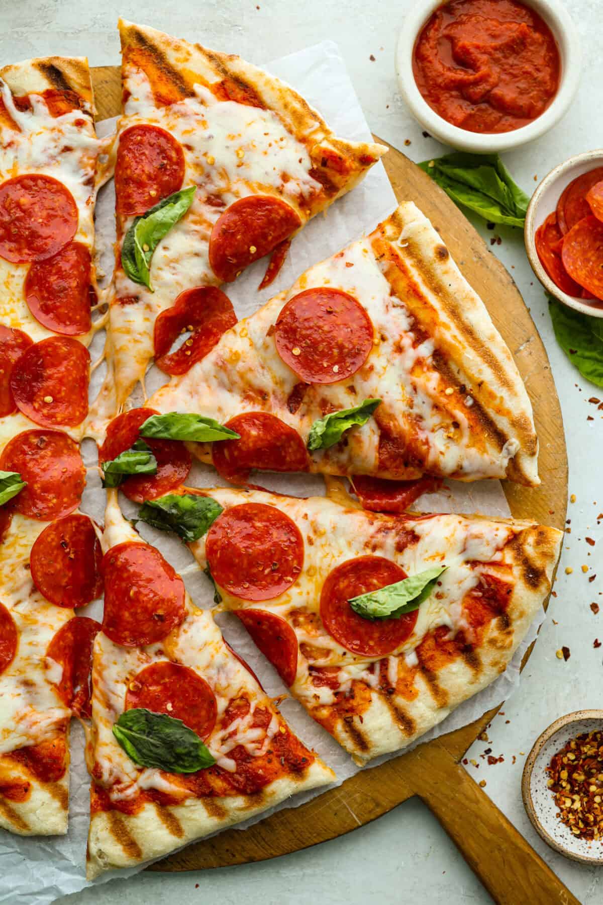 I’m all about pizza and grilling, so when I can combine the two, it’s a win. The grill gives pizza that smoky, crispy flavor you can’t get from the oven. Trust me, this grilled pizza will have you hooked! Overhead shot of grilled pizza cut into slices.