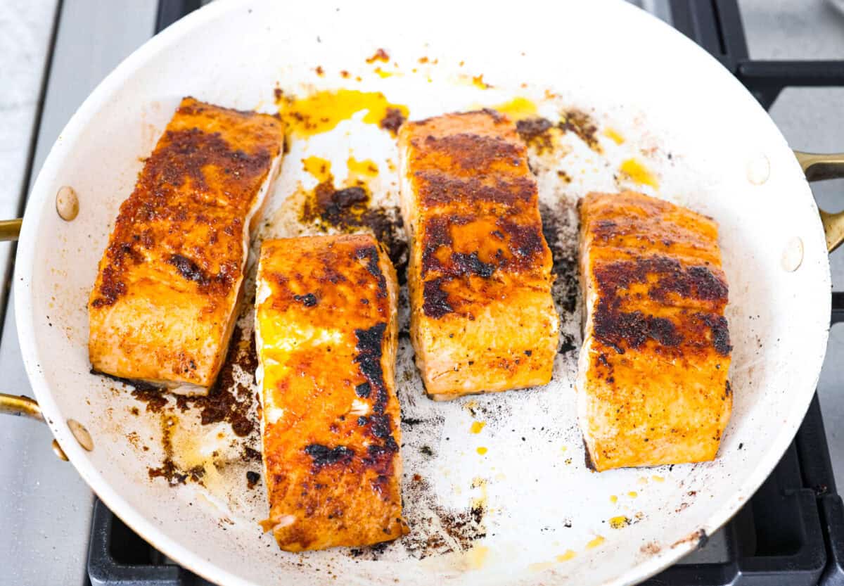 I’m obsessed with salmon, and this Mango Salsa Salmon might just be my new favorite! It’s super flavorful, fast to cook, and somehow my kids don’t fight me on it. That bright, juicy salsa on top? Freaking amazing. I could eat it every night! Filets cooking in a pan on a stove top.