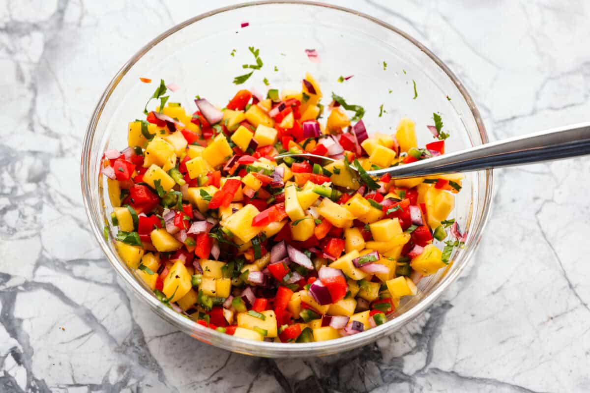 I’m obsessed with salmon, and this Mango Salsa Salmon might just be my new favorite! It’s super flavorful, fast to cook, and somehow my kids don’t fight me on it. That bright, juicy salsa on top? Freaking amazing. I could eat it every night! Bowl of mango salsa ingredients diced and mixed together.
