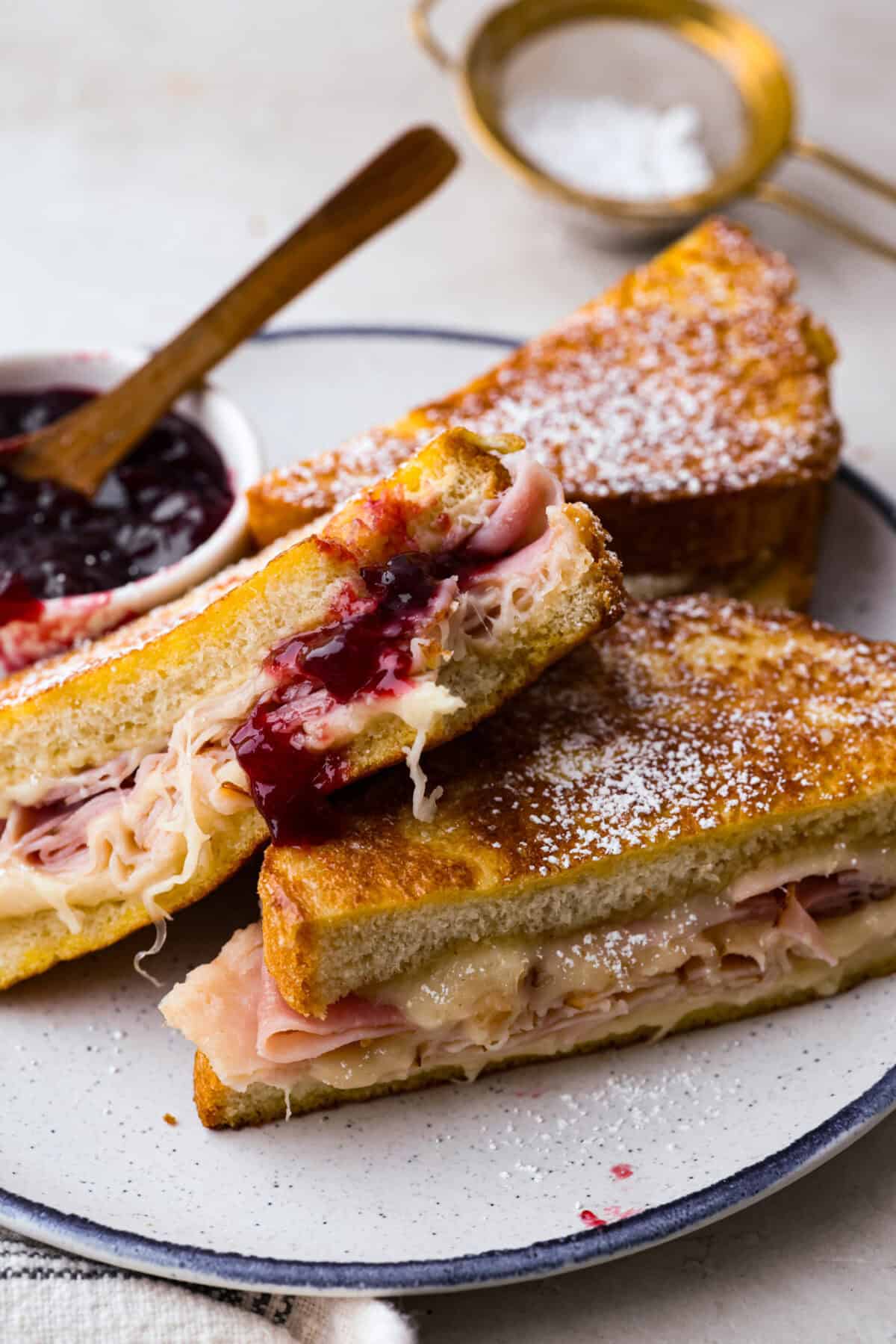 Monte Cristo sliced in half on a plate with raspberry jam. 
