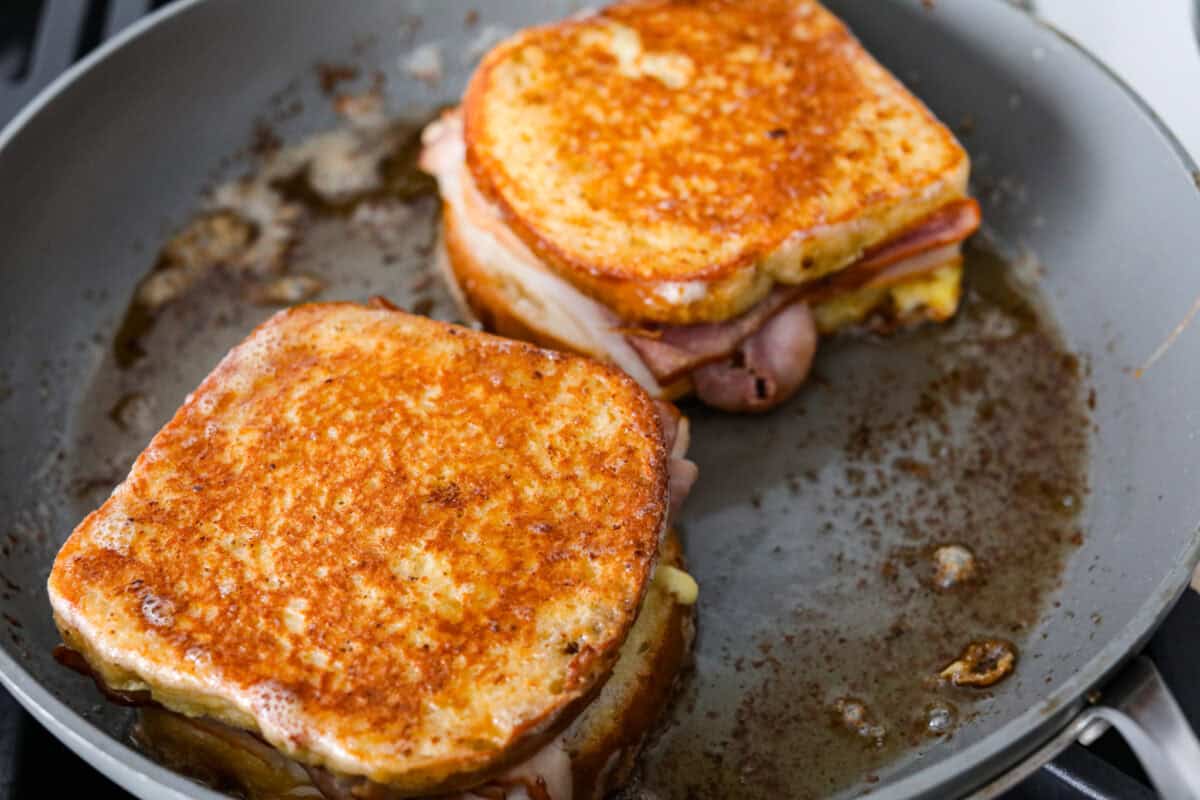 Two Monte Cristo sandwiches toasting in the skillet. 