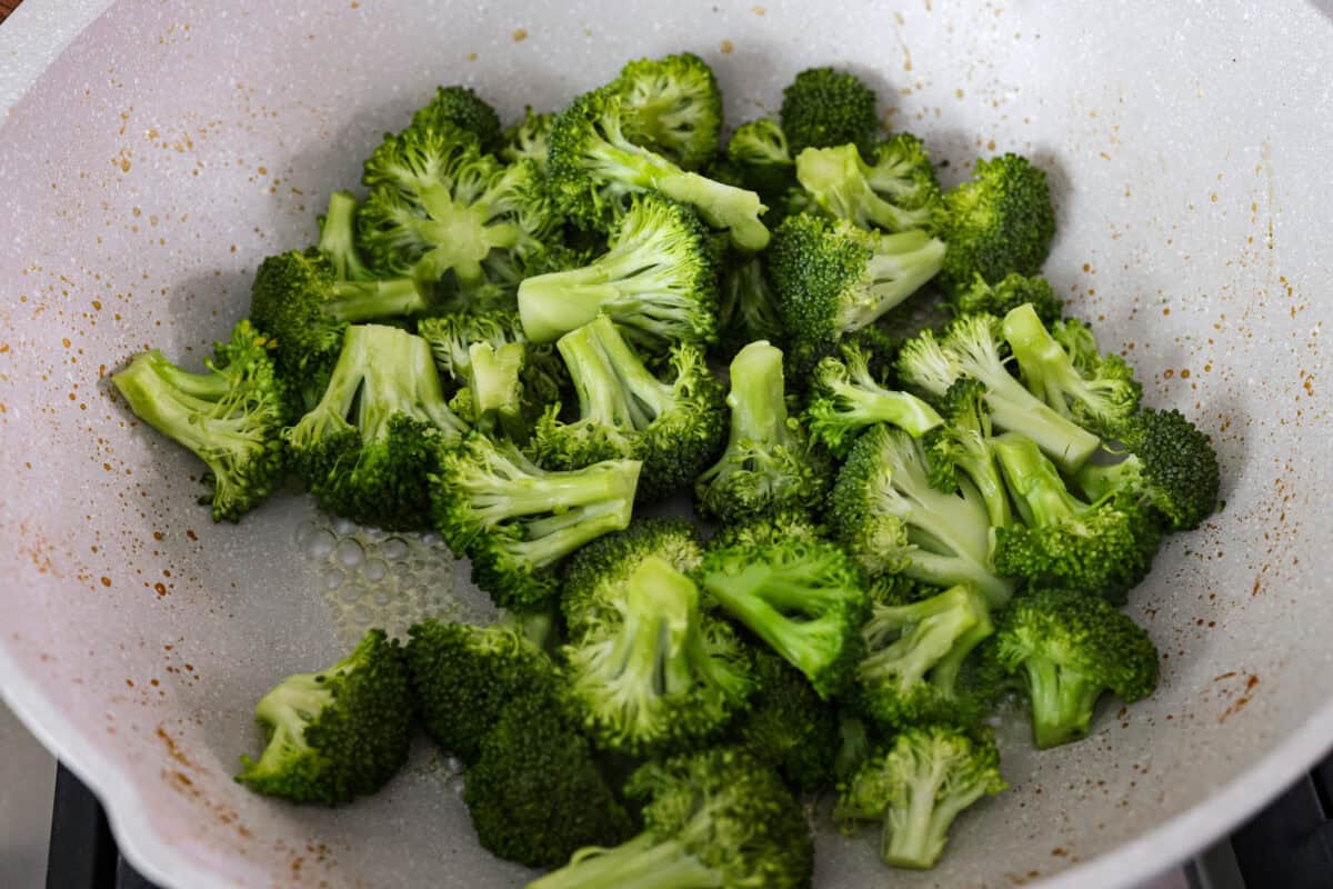 Broccoli steaming in a skillet.