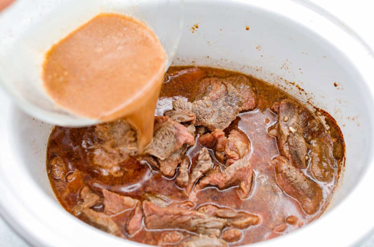 Cornstarch and some of the sauce being added back to the crockpot. 