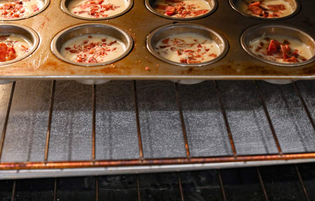 I’ve been hooked on Starbucks egg bites for years, but not the price! This homemade version is just as fluffy and flavorful, and makes the perfect grab-and-go, protein-packed breakfast. Muffin tin with egg and bacon in the oven over a water bath.