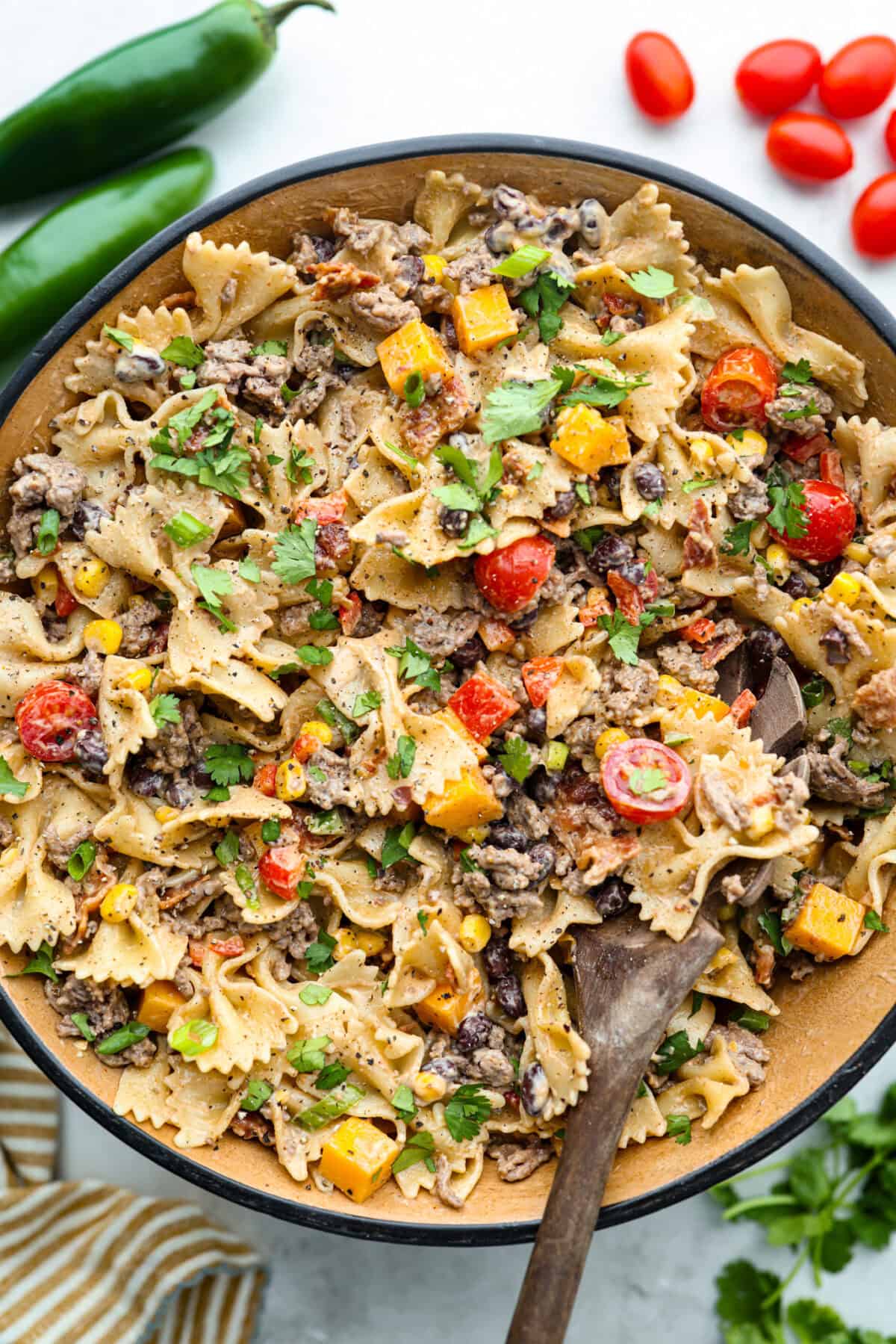 Yeehaw! My cowboy pasta salad is loaded with beef, bacon, beans, and all the fixings for all you cowboy lovers. You'll get all the flavors of the Wild West tossed in the tastiest cowboy salad dressing. Overhead shot of cowboy pasta salad in a serving dish.