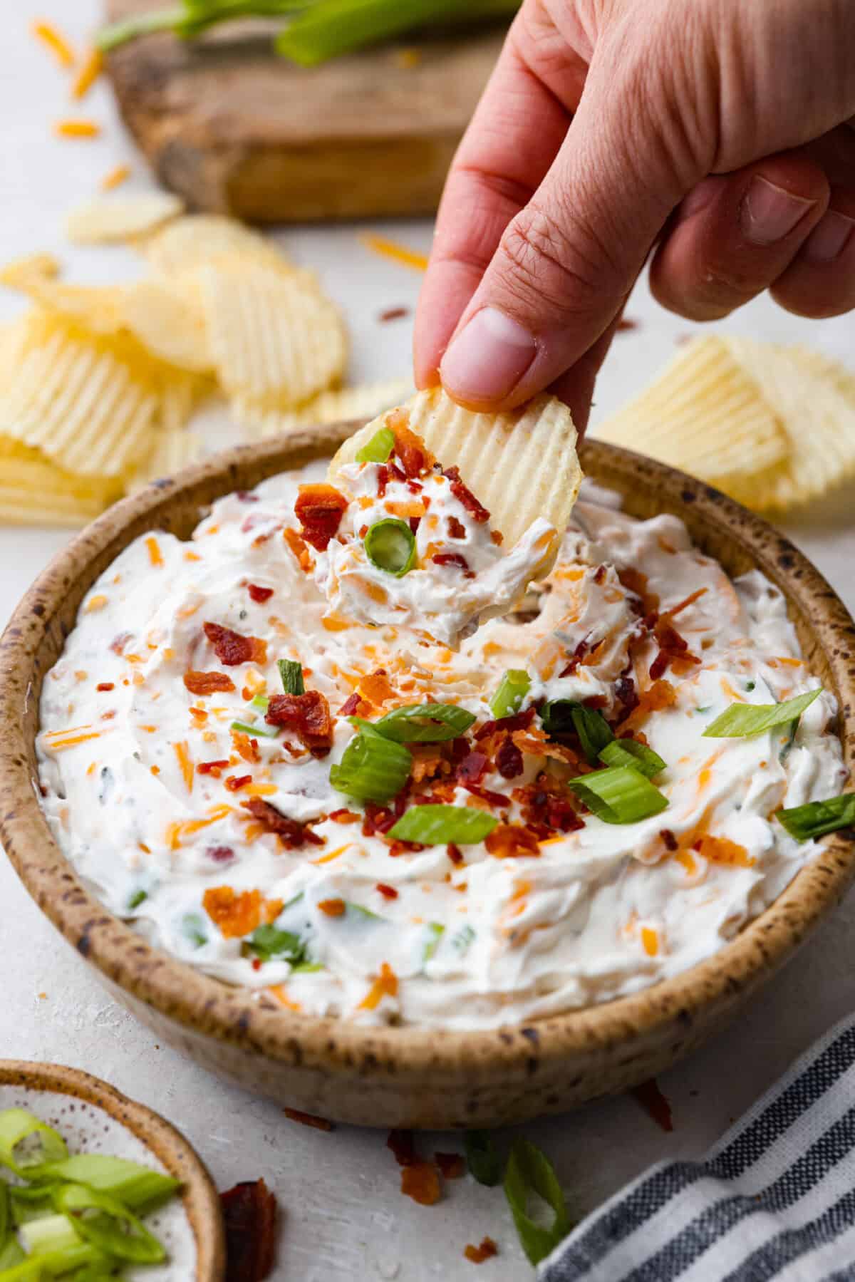 Creamy, cheesy, and loaded with crack dip flavor! This 6-ingredient appetizer is served cold and ready in just 10 minutes. Good luck keeping it on the table. Someone taking a scoop of the completed dip with a chip.