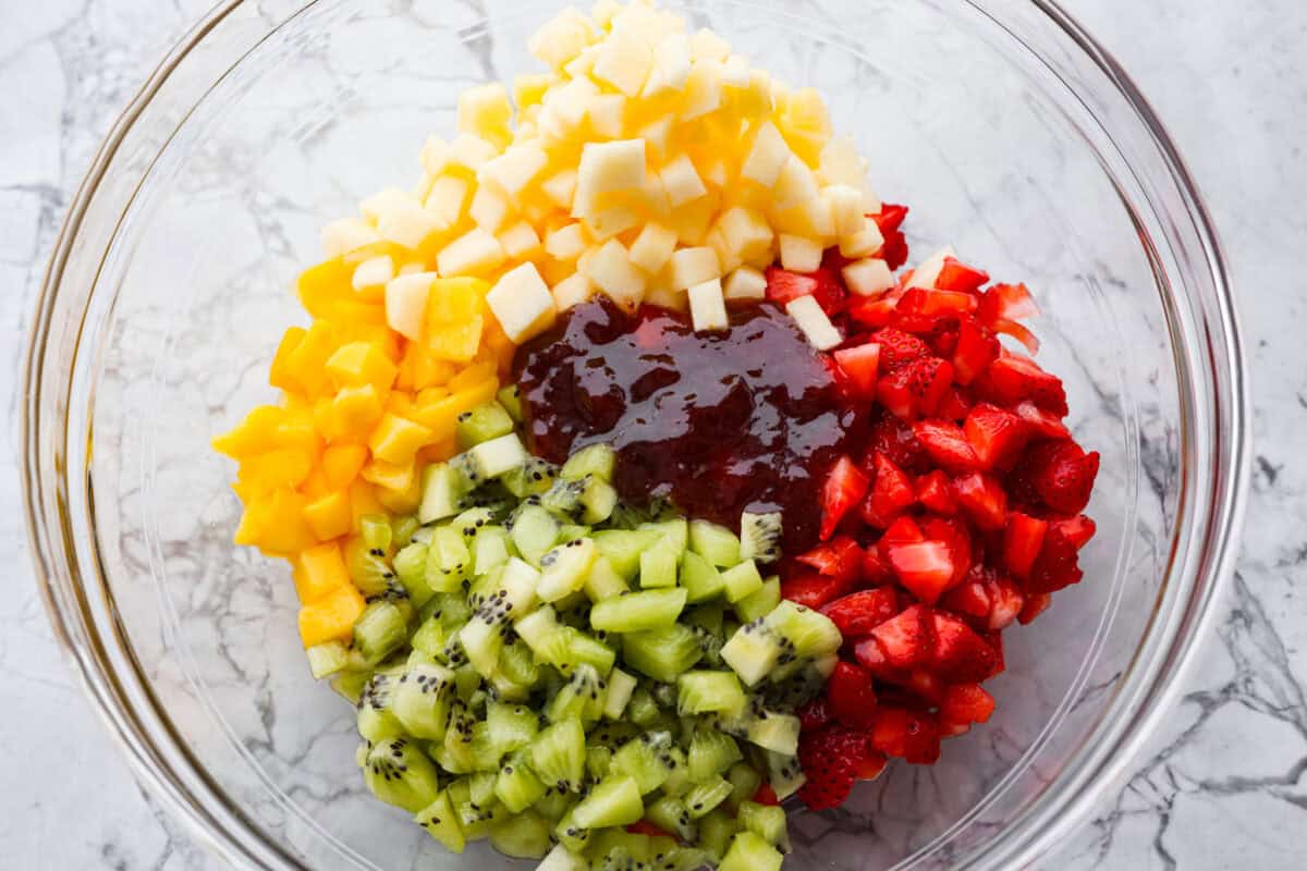 Raspberry jam added to the bowl of diced fruit. 