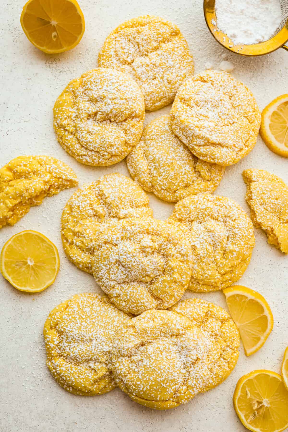 Overhead shot of lemon cake mix cookies dusted with powdered sugar with lemon slices around them. 
