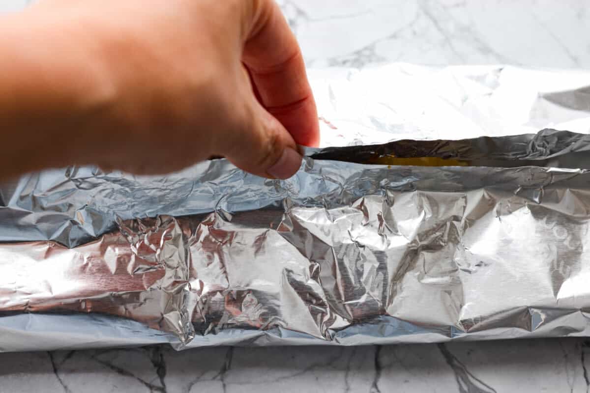 These meatball foil packets have juicy meatballs, sweet pineapple, colorful veggies, covered in sticky teriyaki sauce, and grilled to perfection. Easy to make, fun to eat, and no dishes to wash! Yes, please! Someone sealing up the foil packets.