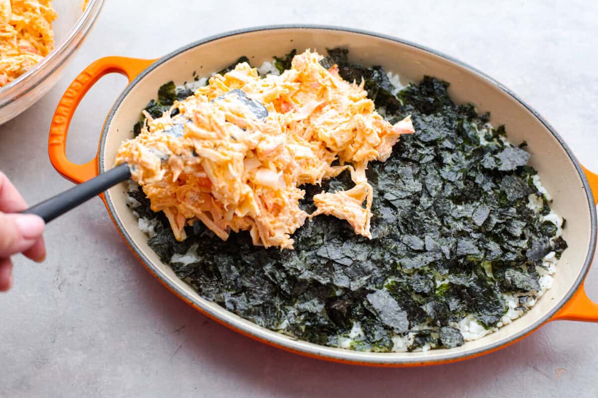 Fish and cream cheese mixture being spread over the seaweed layer. 