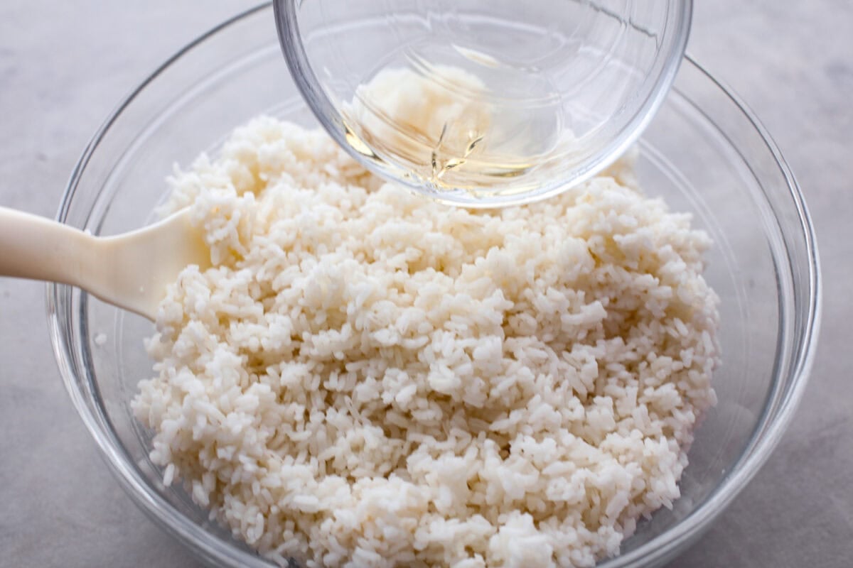 Adding the sugar and vinegar mixture to the cooked rice. 