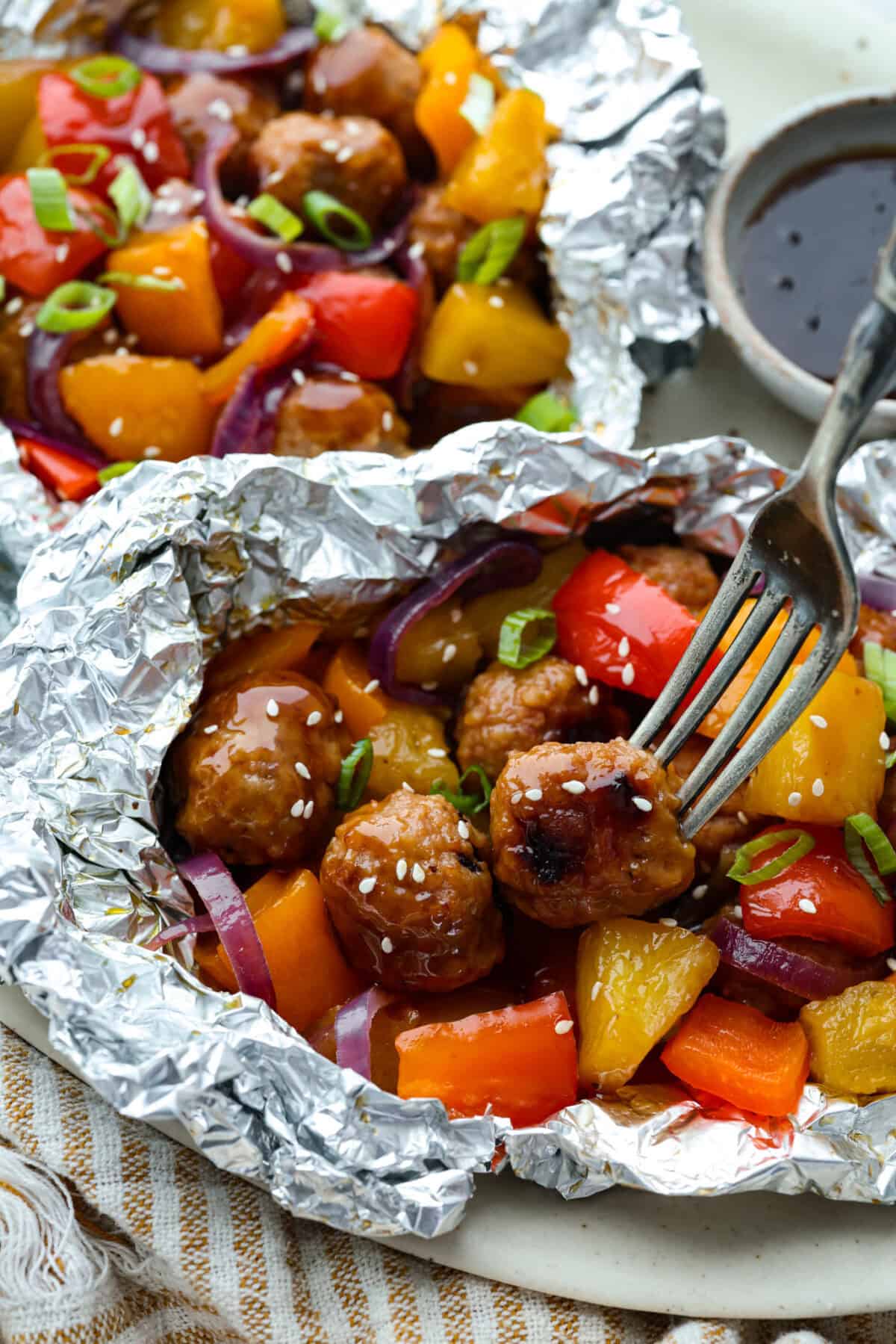 These meatball foil packets have juicy meatballs, sweet pineapple, colorful veggies, covered in sticky teriyaki sauce, and grilled to perfection. Easy to make, fun to eat, and no dishes to wash! Yes, please! Meatball foil packets with veggies and pineapple.
