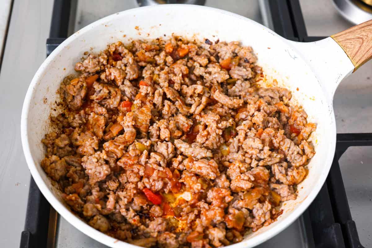 Sausage cooking an a skillet with salsa added to it. 