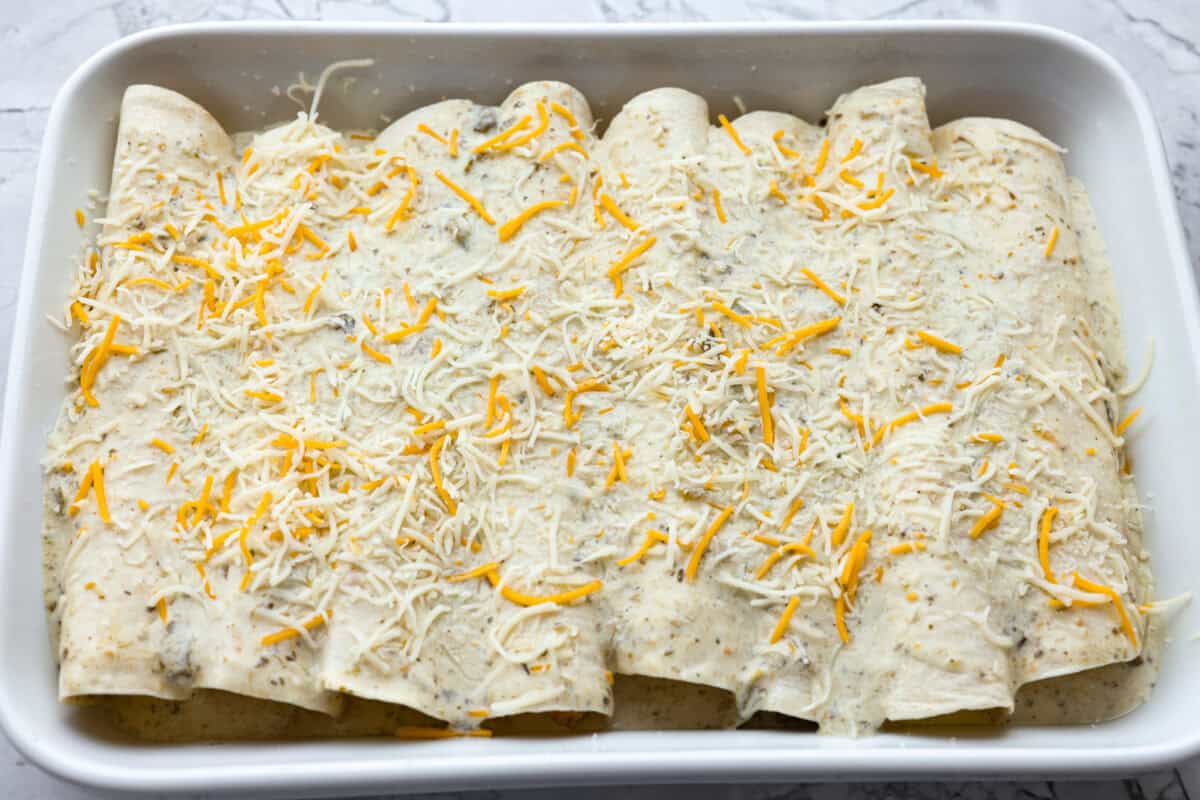 All of the breakfast enchiladas rolled up in the pan with creamy enchilada sauce on top and cheese sprinkled on as well. 