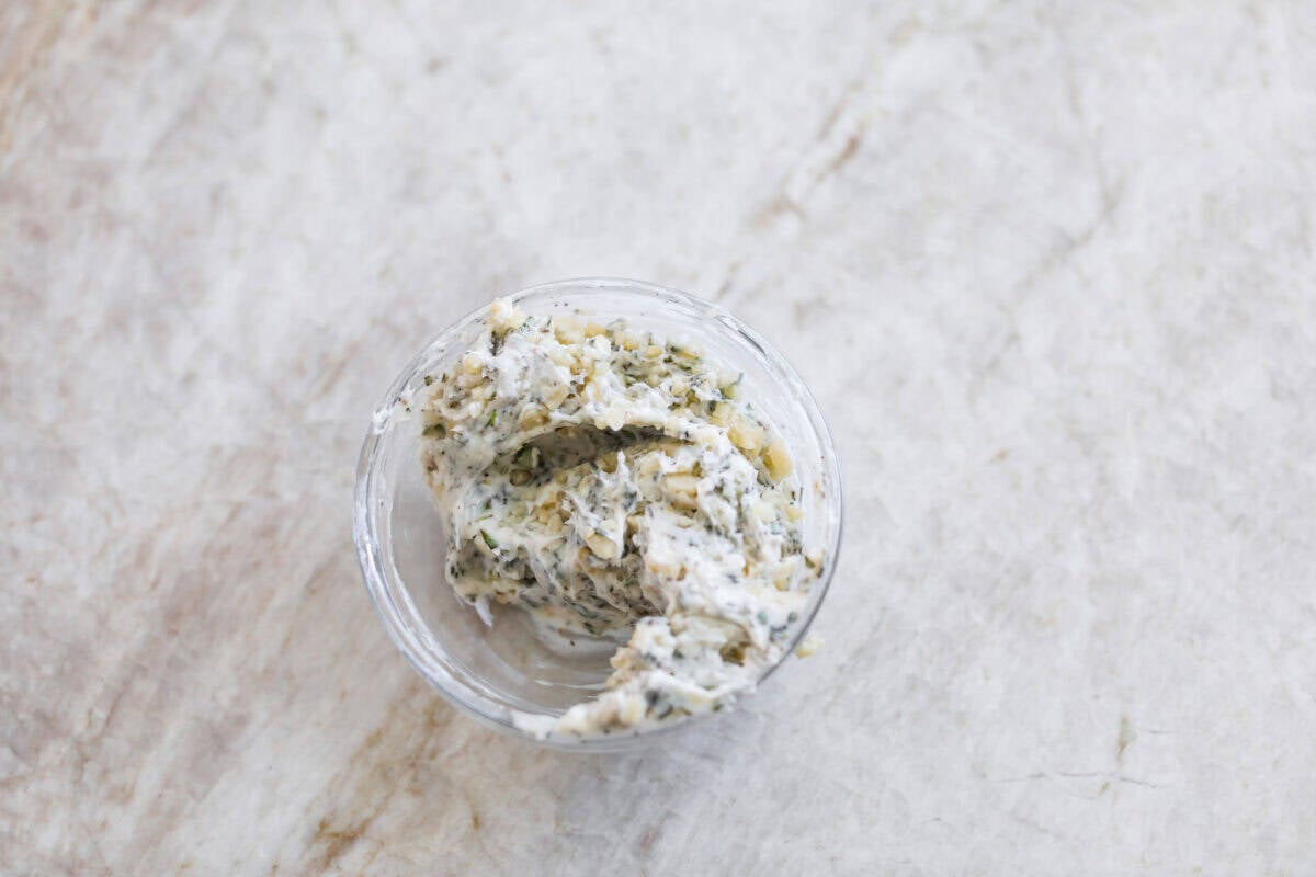 Bowl of the butter mixed with garlic and herbs.