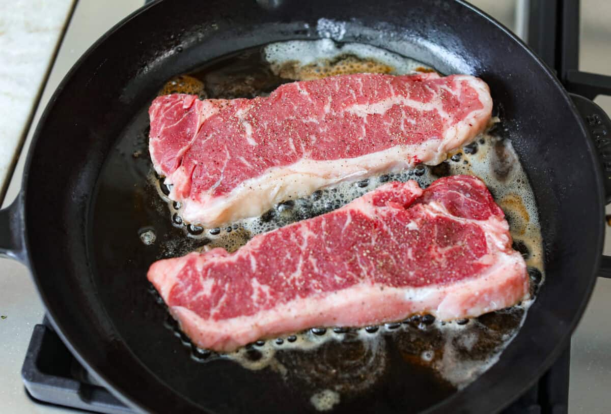 Steaks sizzling in a hot skillet. 