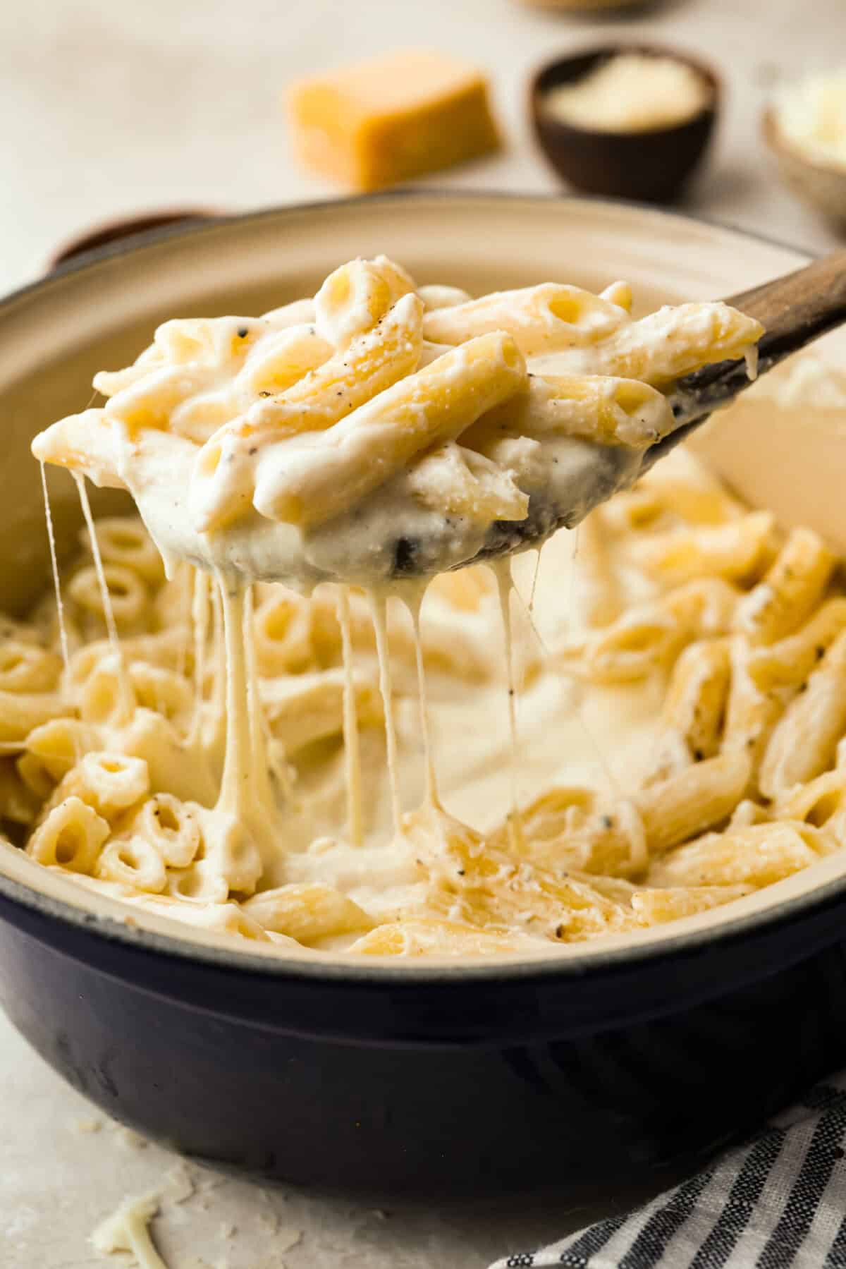 Craving something cozy, cheesy, and totally irresistible? My four cheese pasta brings comfort with a creamy ricotta base and a melty mix of easy-to-find Italian cheeses. It’s indulgent and totally hits the flavor jackpot! Someone lifting a scoop of four cheese pasta out of the pan.