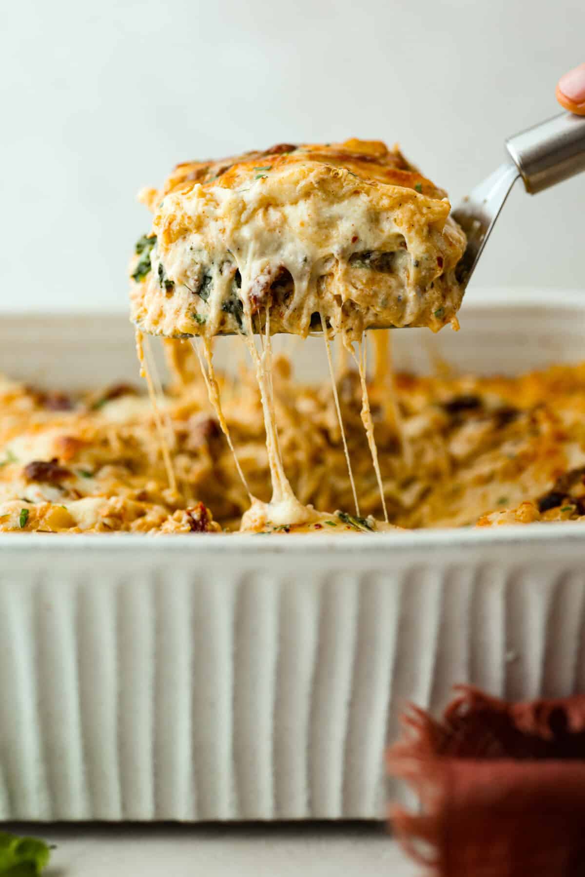 They don’t call it Marry Me Lasagna for nothing! One bite of the creamy sauce, tender chicken, and melty cheese, and everyone will be saying, "YES!" Side shot of someone pulling a slice of marry me lasagna out of the pan with cheesy sauciness stretching from the main casserole.