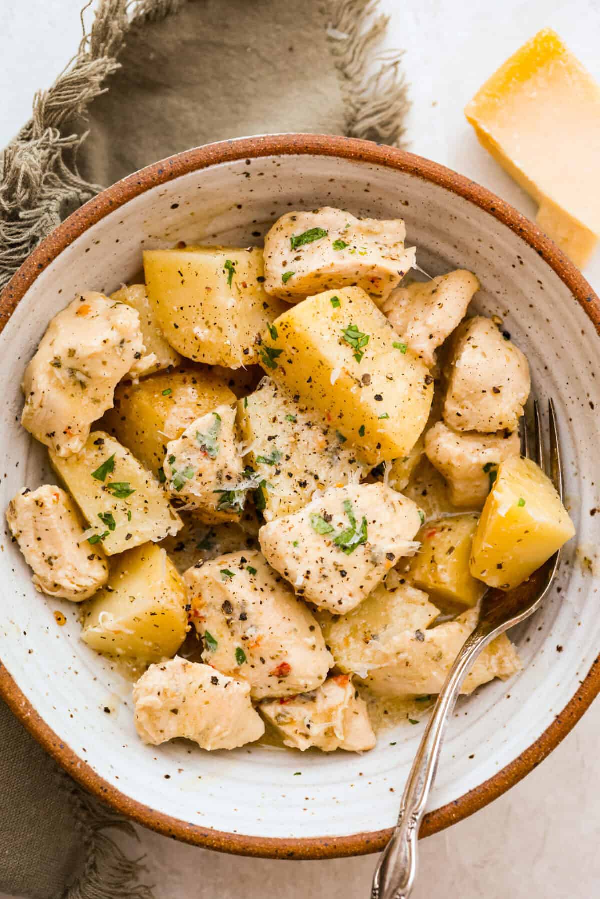 This viral slow cooker Parmesan garlic chicken has juicy meat, tender potatoes, and a sauce so rich and creamy that scooping it with a spoon won’t cut it. You’ll want to drink it, or let’s be real, bathe in it. Bowl of individual serving of slow cooker parmesan garlic chicken.