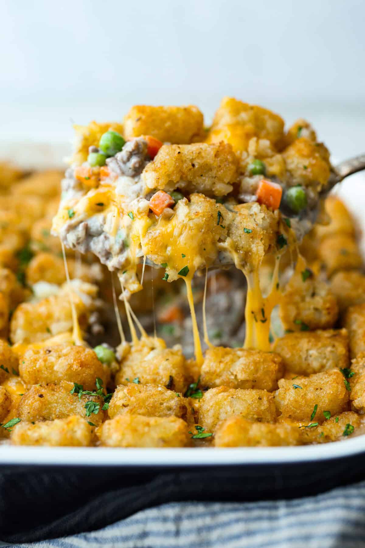 If you love shepherd’s pie, you’ve got to try this Tater Tot Casserole! It’s the ultimate lazy-girl version, with tots instead of mashed potatoes, melty cheese, hearty beef, and total comfort in every bite. The kids will absolutely devour it. Side shot of a scoop of tater tot casserole being lifted out of the pan.