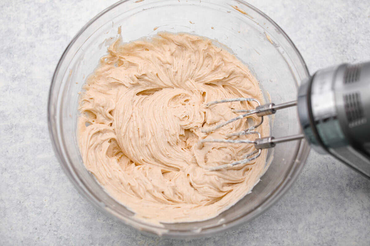 Caramel Apple Pie Lush is the easiest fall dessert you’ll ever make! With layers of buttery crust, creamy cheesecake, spiced apples, caramel, and whipped topping, it’s a yummy fall treat that is so much easier than baking a pie from scratch! Cream cheese, sugar, vanilla, and seasonings added to a bowl and are being mixed together with a hand mixer.