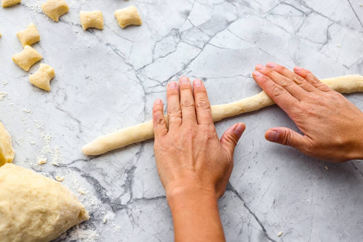 Someone rolling out dough into strips/snakes.