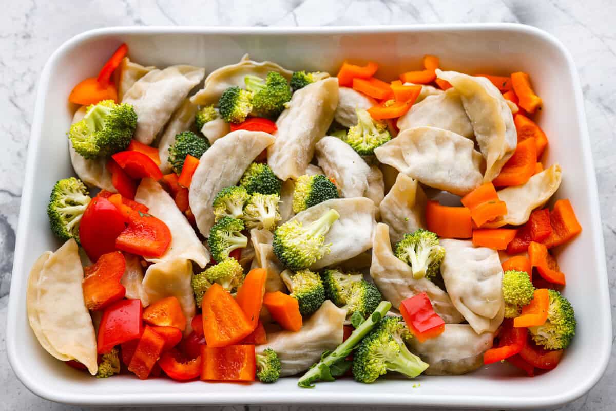 Potsticker casserole is all the tasty fun of potstickers in a warm, baked dish. Soft dumplings, fresh veggies, and a rich sauce cook together for a fast, easy, and filling meal. Potstickers added to the bottom of a casserole dish with vegetables added to the top.