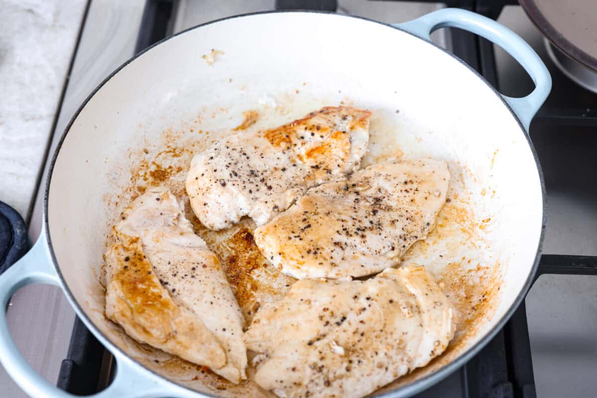 Tuscan garlic skillet chicken is one of those dinners I make and then wonder why I don’t make it more often. Juicy chicken and sun-dried tomatoes all cook together in one skillet. No heavy cream needed. Just fresh, bold flavor in 30 minutes! Chicken cooking in a skillet.