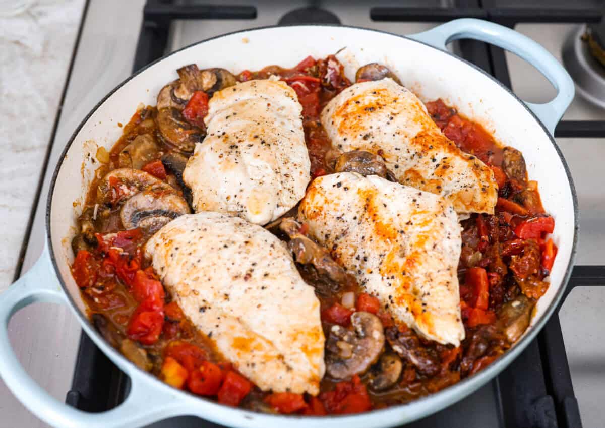 Tuscan garlic skillet chicken is one of those dinners I make and then wonder why I don’t make it more often. Juicy chicken and sun-dried tomatoes all cook together in one skillet. No heavy cream needed. Just fresh, bold flavor in 30 minutes! Chicken added back to the veggies in the skillet.