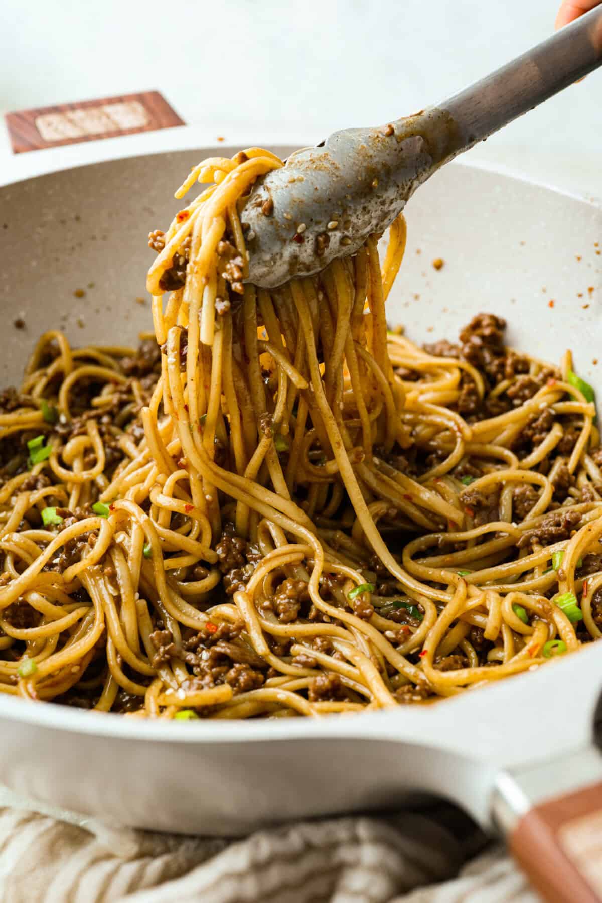 Someone lifting a portion of the Korean beef noodles out of the pan. 