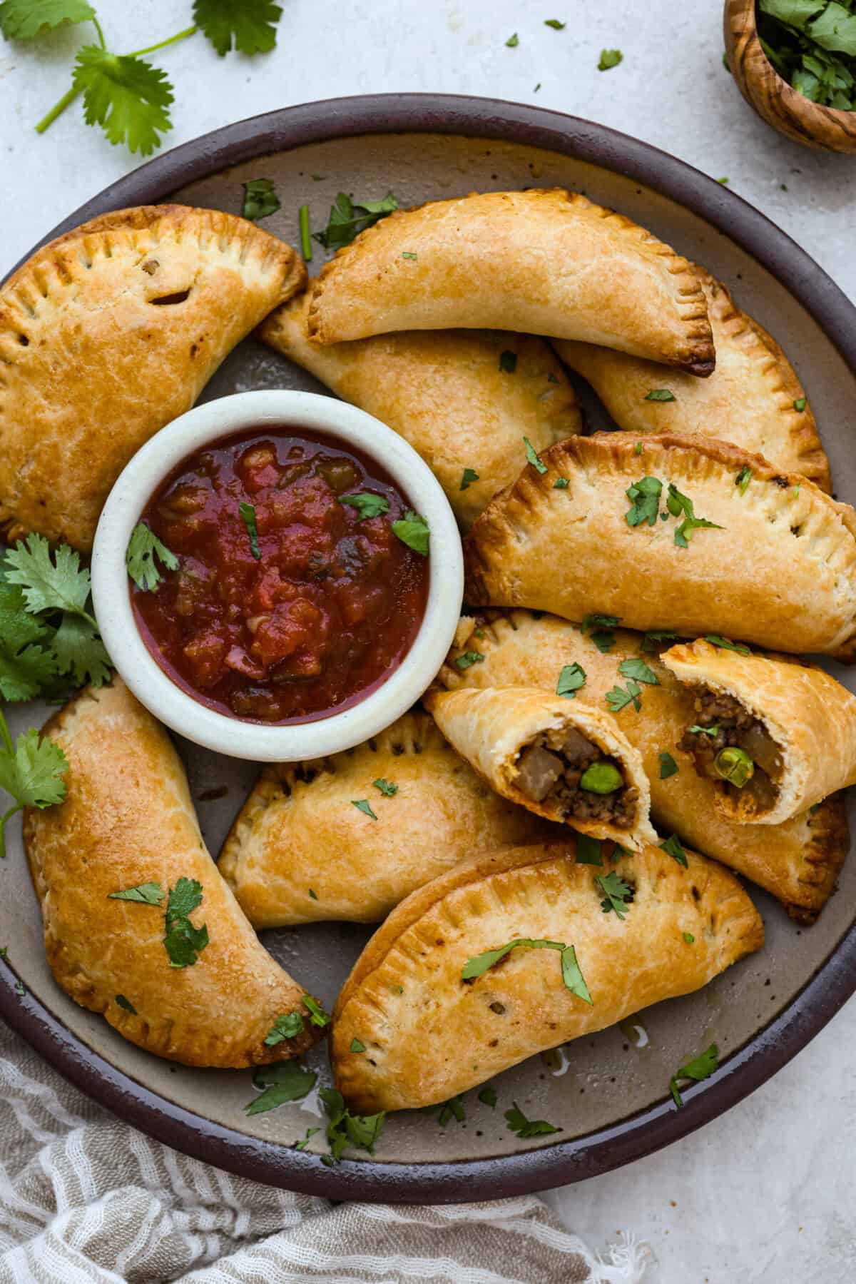Plate of homemade empanadas with a small bowl of salsa.