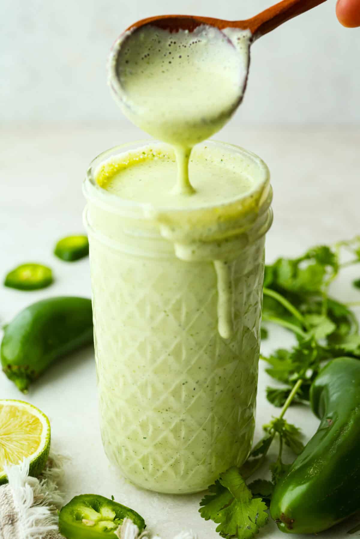 Spice meets creamy! This Jalapeño Ranch Dressing is cool, tangy, and just the right amount of zesty heat. Perfect for drizzling, dipping, or smothering on everything from salads to tacos. Someone getting a spoon of jalapeño ranch dressing from a small jar.