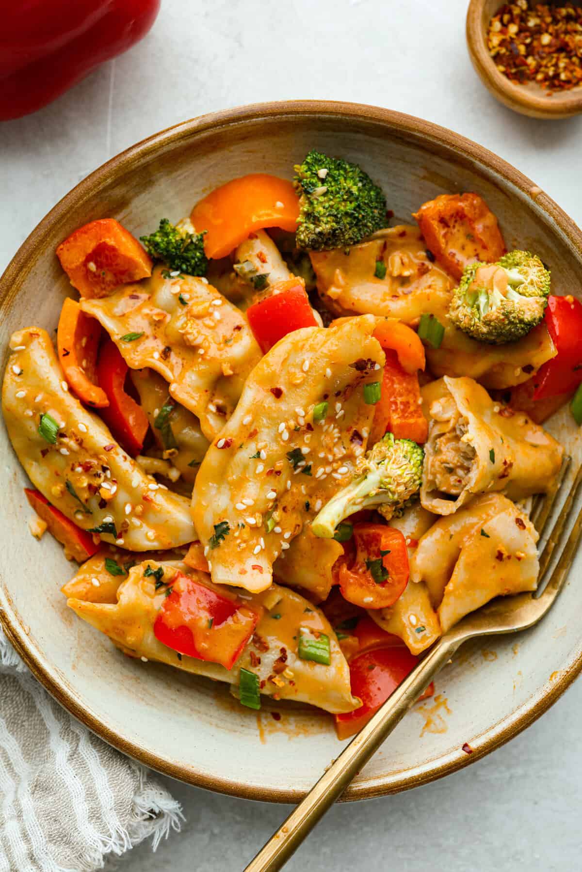 Potsticker casserole is all the tasty fun of potstickers in a warm, baked dish. Soft dumplings, fresh veggies, and a rich sauce cook together for a fast, easy, and filling meal. Bowl of potsticker casserole with a gold fork.