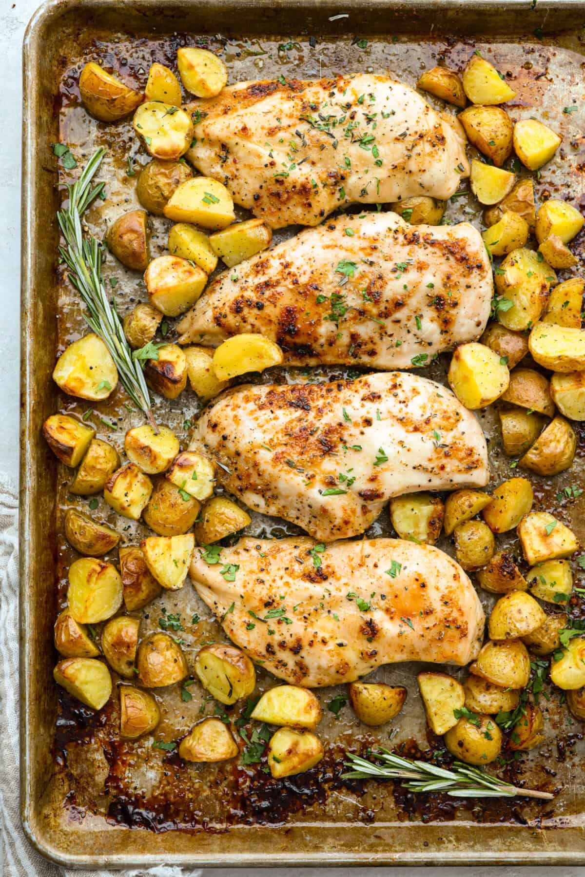Baked buttery herb chicken with potatoes is pure comfort on a plate! I love tossing everything together in one pan and letting it cook! It saves time and lets all those delicious flavors meld for the juiciest, flavorful chicken and soft, savory potatoes. Cooked herb chicken and potatoes on a sheet pan with fresh herbs.