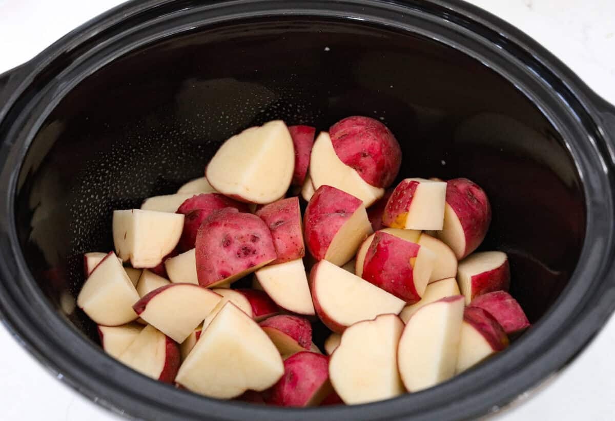 Potatoes in the bottom of the crockpot.