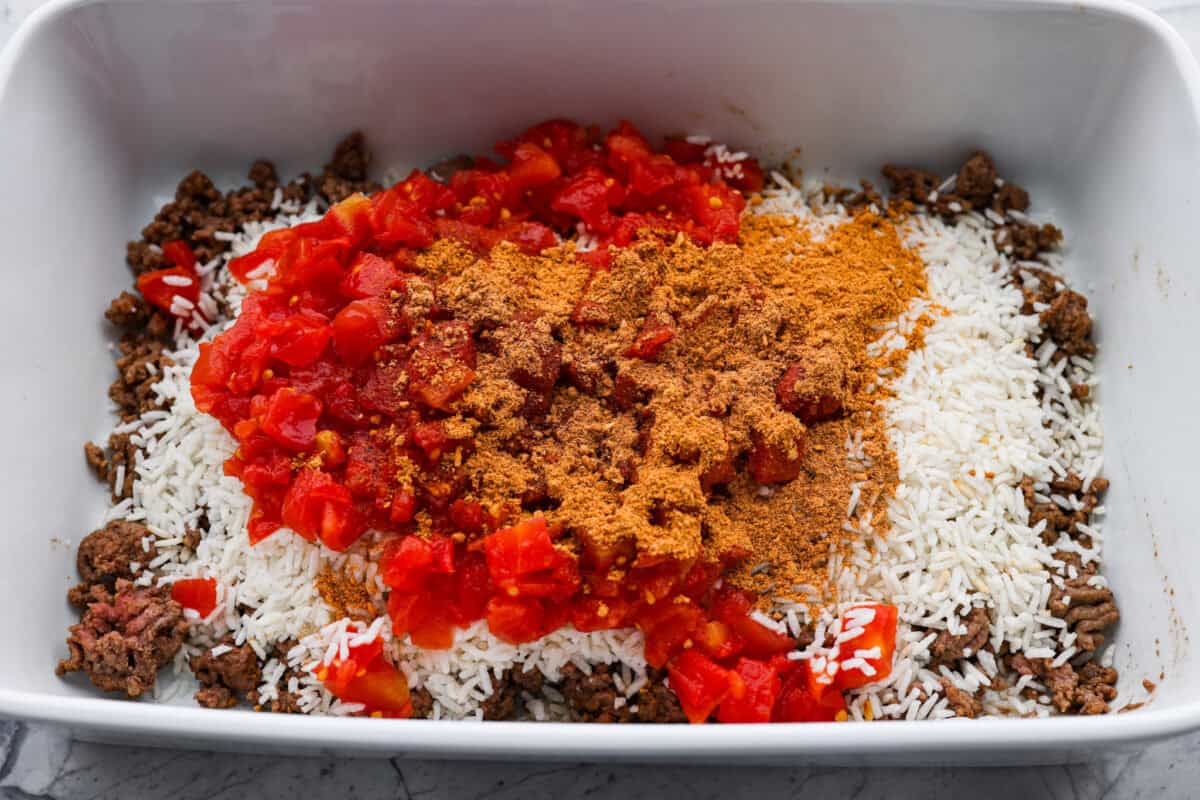 This is about to change your taco game forever! No shell needed! This dump-and-go taco rice is so easy and made with just 6 ingredients. Throw it together, top it your way, and boom, you’ve got a totally unique and delicious taco night! Cooked ground beef in the bottom of a casserole dish topped with minute rice, Rotel and taco seasoning.