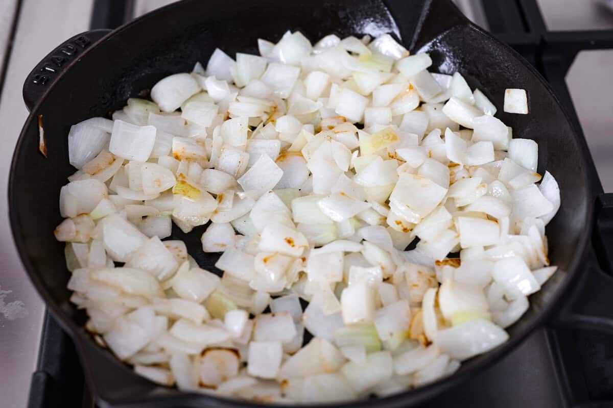 My Tennessee Onion Dip is a family-party legend. Everyone always begs me to bring it, and for good reason, the sweet onion flavor baked with gooey cheese and seasonings is absolutely irresistible! Skillet full of chopped onions cooking.