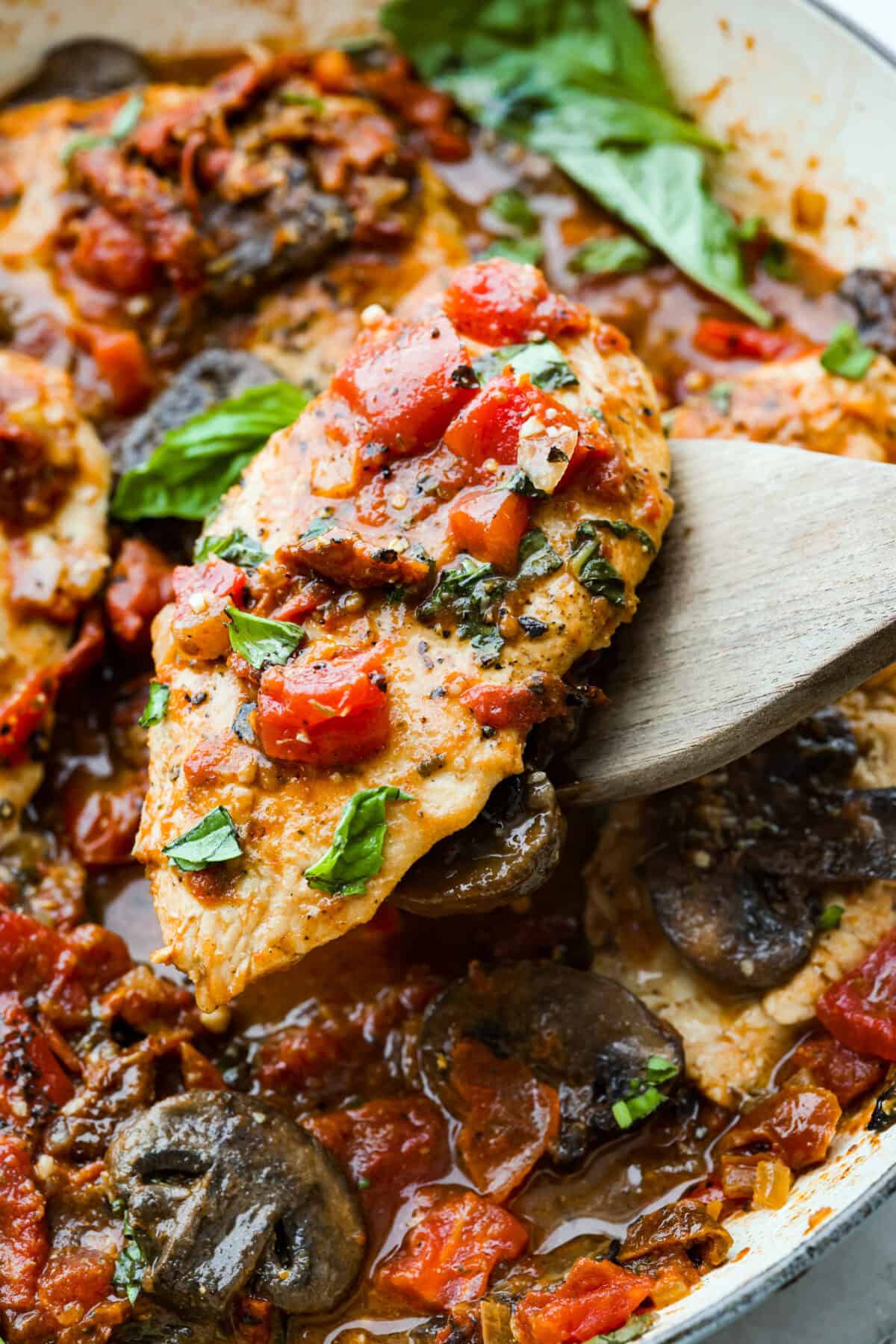 Tuscan garlic skillet chicken is one of those dinners I make and then wonder why I don’t make it more often. Juicy chicken and sun-dried tomatoes all cook together in one skillet. No heavy cream needed. Just fresh, bold flavor in 30 minutes! Close up shot of a Tuscan garlic skillet chicken breast.
