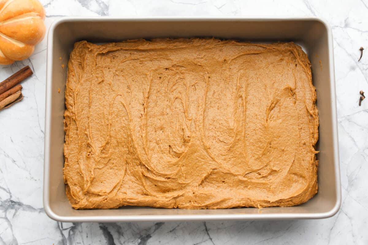 This 2 ingredient pumpkin cake comes together in minutes and bakes up perfectly spiced, tender, and fluffy every single time. It’s the ultimate dessert for any fall gathering or when the sweet tooth hits! Cake batter mixed and spread out in the bottom of a 9x13 pan.