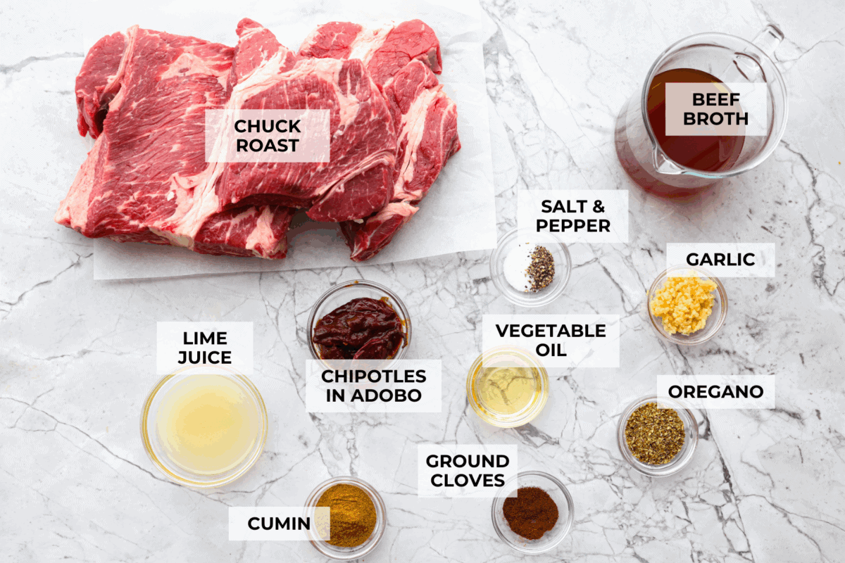 Slow cooker barbacoa beef simmers all day in smoky chipotle, tangy lime, and warm spices until it falls apart. It’s perfect for tacos, burritos, bowls, or nachos, all with that taquería-style flavor at home. Overhead shot of labeled ingredients.