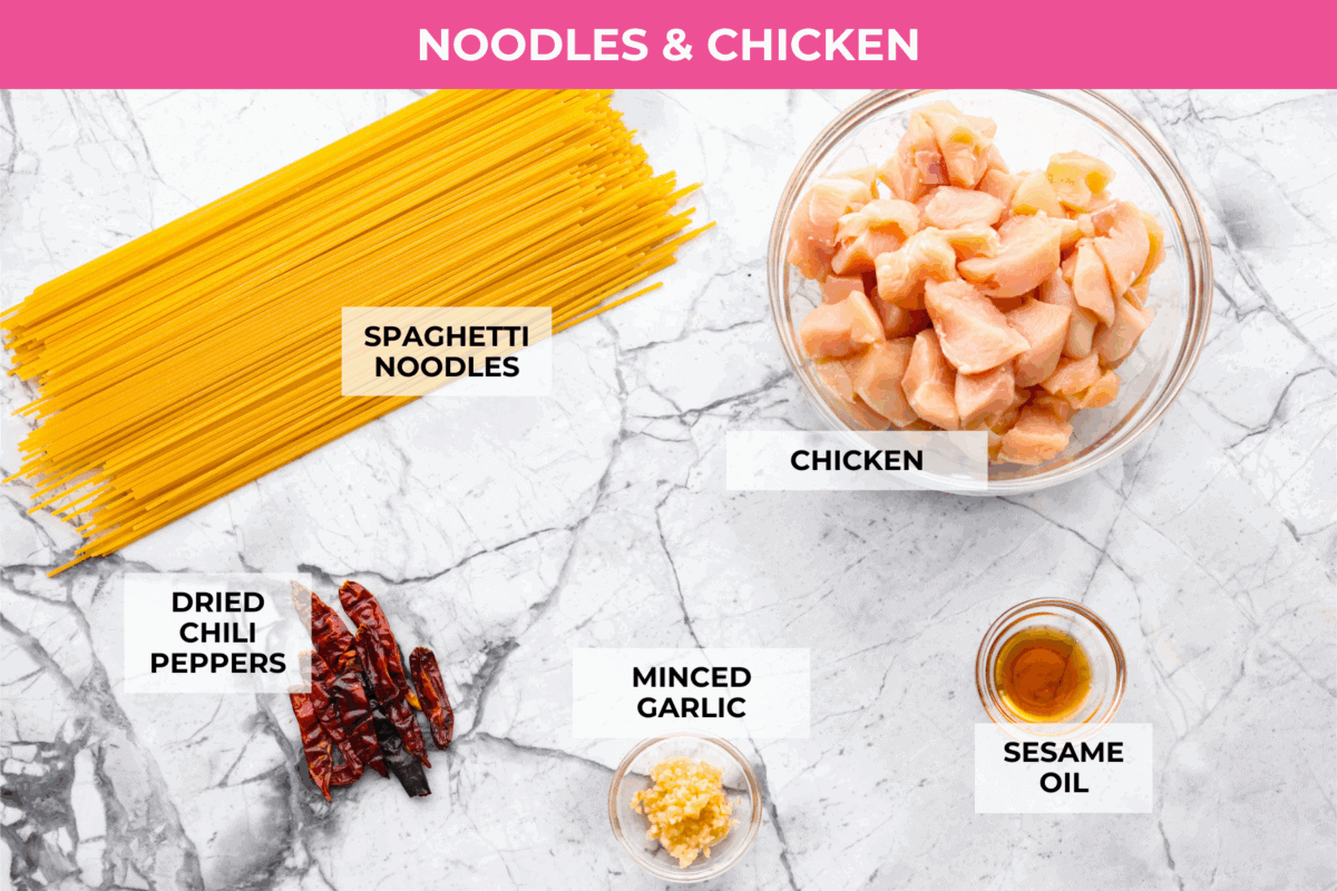 Skip the takeout, these Kung Pao Chicken Noodles are spicy, saucy, and loaded with flavor! Tender chicken, chewy noodles, crunchy peanuts, and a kick of heat all come together in one quick and easy dish that’s perfect for weeknight dinners. Overhead shot of then labeled chicken and noodles ingredients.