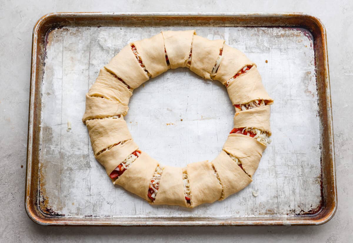 Pizza night just got a glow-up! This fun pull-apart pizza ring is perfect for family dinner, game day, or a party snack. Easy to make, endlessly customizable, and totally kid-approved, you’ll be reaching for slice after slice! Each sunburst point of crescent dough folded over the toppings and cheese to create the pizza ring.