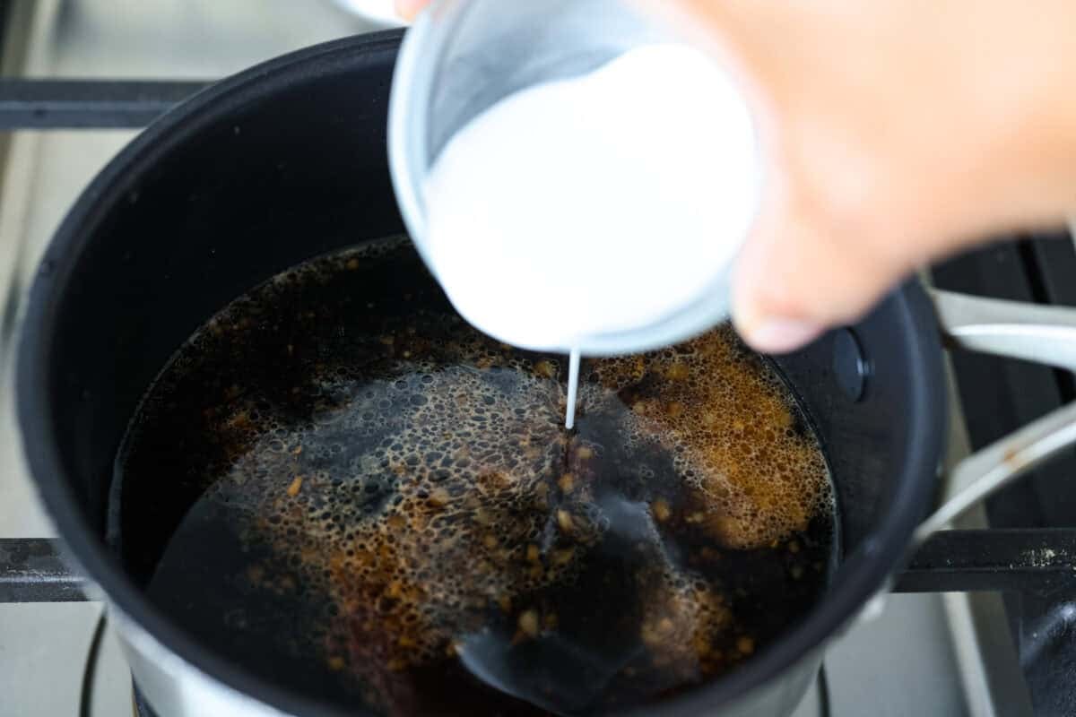 Cornstarch slurry being added to the sauce to thicken it.