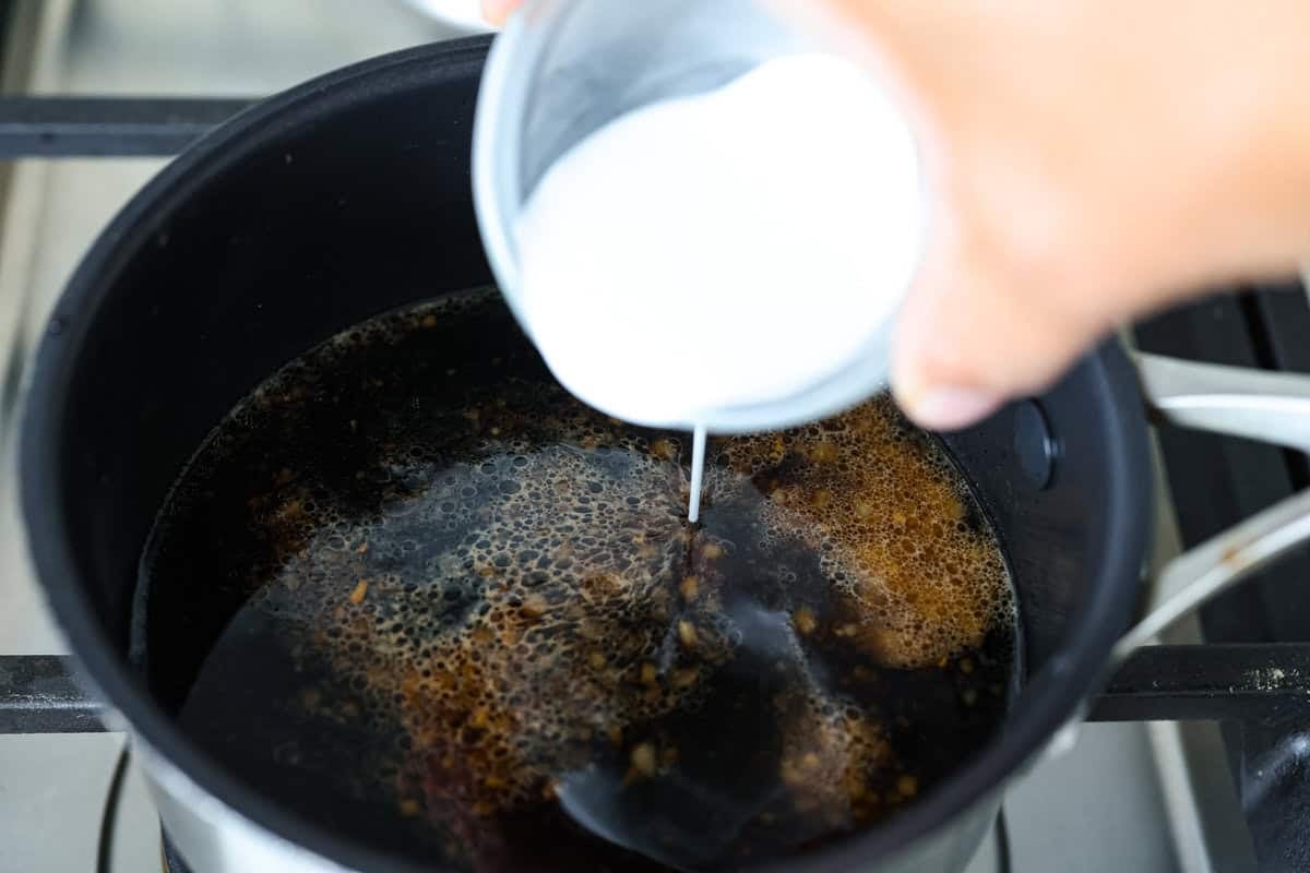 Air fryer teriyaki salmon is the best fast and tasty meal! The salmon cooks up perfectly tender with crisp edges, then gets coated in a glossy, sweet-and-savory teriyaki glaze that I know you'll love! Cornstarch slurry being added to the sauce to thicken it.