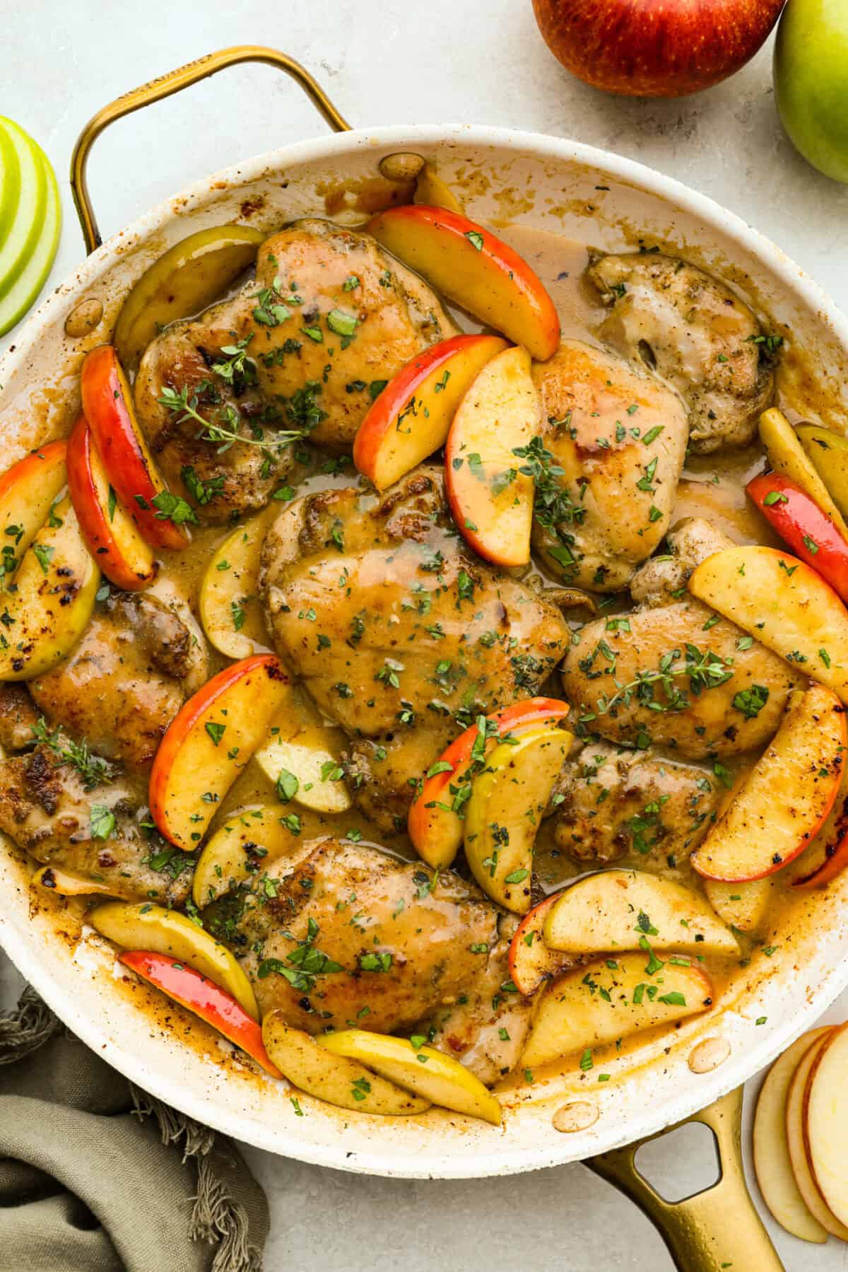 Apple cider chicken thighs bring all the best fall flavors to your plate! Juicy chicken, caramelized apples, and a rich cider sauce for the ultimate cozy dinner. Overhead shot of apple cider chicken thighs in a skillet.