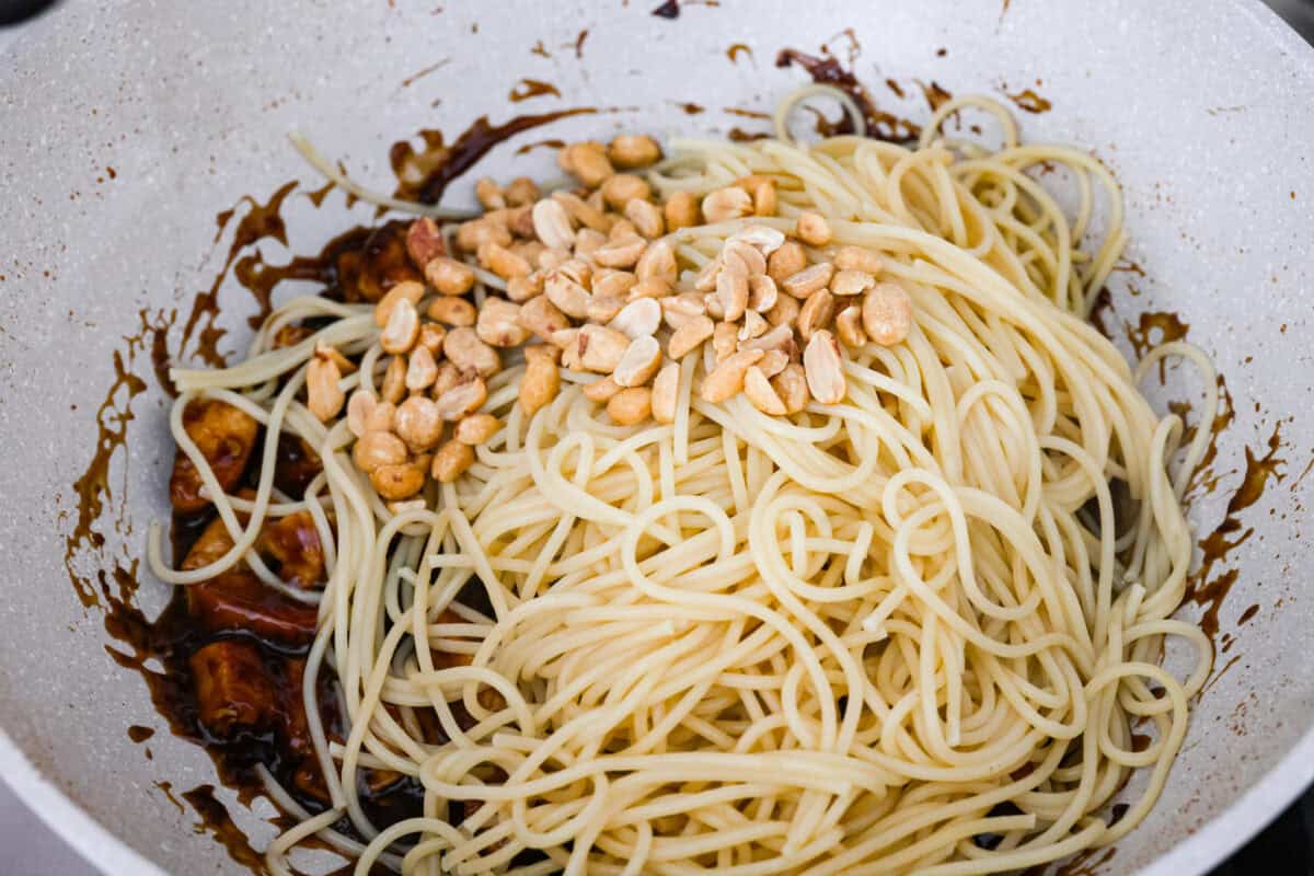 Skip the takeout, these Kung Pao Chicken Noodles are spicy, saucy, and loaded with flavor! Tender chicken, chewy noodles, crunchy peanuts, and a kick of heat all come together in one quick and easy dish that’s perfect for weeknight dinners. Cooked noodles and peanuts added to the sauce and chicken in the skillet.