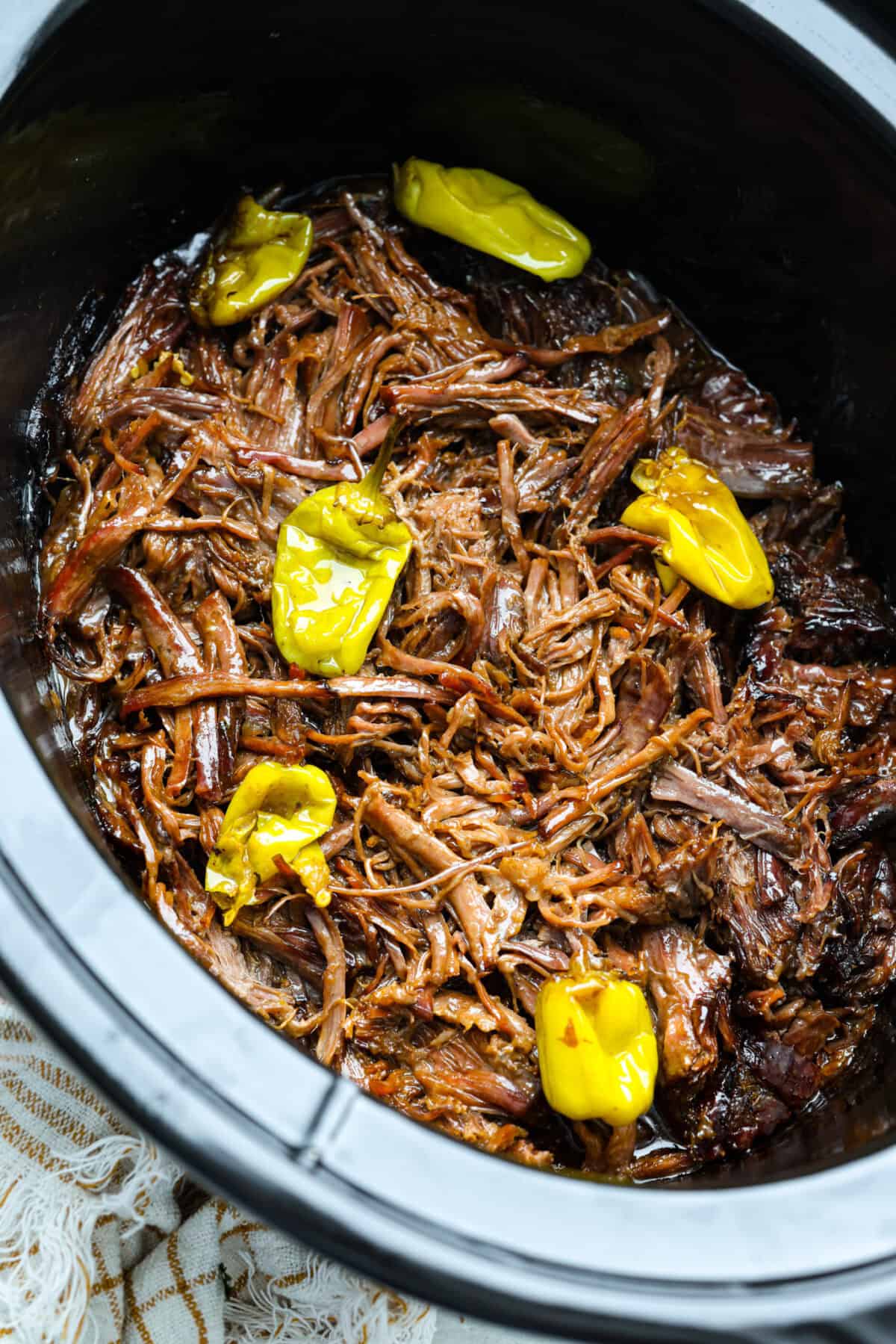 This Mississippi pot roast is melt-in-your-mouth tender, full of rich flavor, and couldn’t be easier. Just five ingredients and your slow cooker does all the work! It's a Sunday favorite at our house, and I know you'll love it too! Overhead shot of Mississippi pot roast shredded in the crockpot.