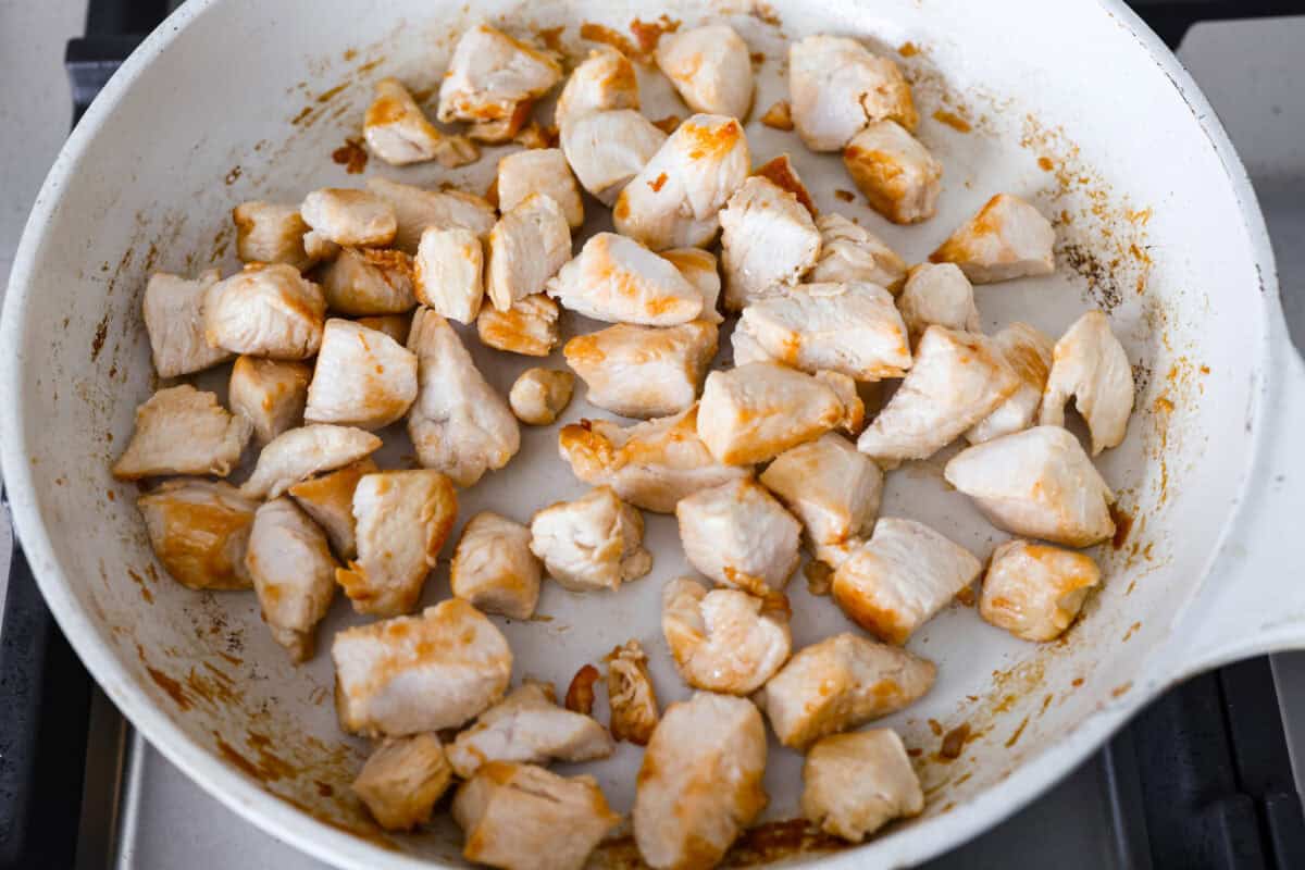 This creamy Tuscan chicken orzo bake is the kind of dinner you’ll want on repeat! Tender chicken, orzo, and sun-dried tomatoes bake together in one pan for an easy, comforting weeknight meal. Cubed chicken cooking in a skillet.