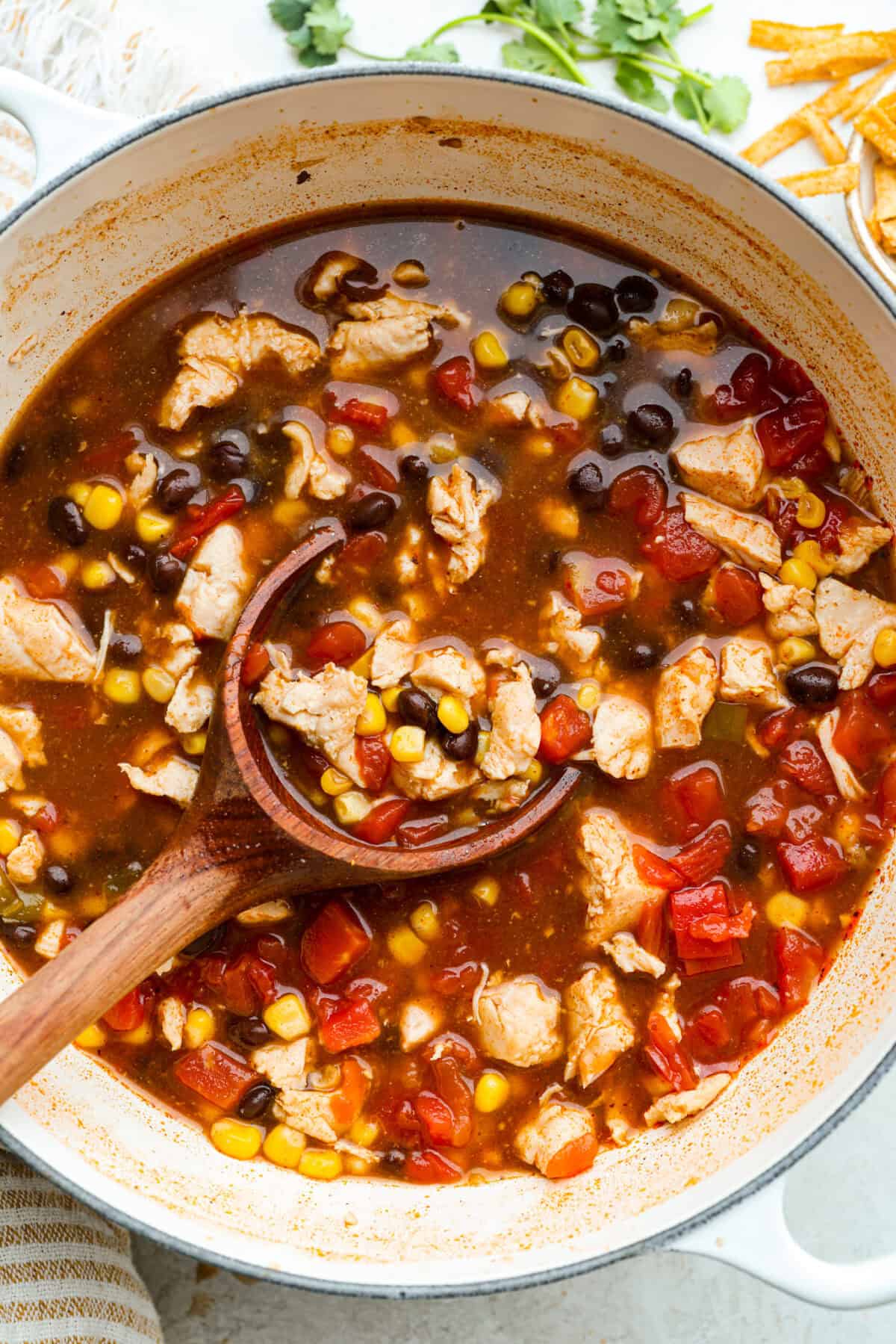 It doesn't get any easier than this 8 Can Chicken Tortilla Soup! Dinner is ready in minutes! Just open, dump, heat, and enjoy bold, delicious flavor in no time! Pot of 8 can chicken tortilla soup with a wooden ladle.